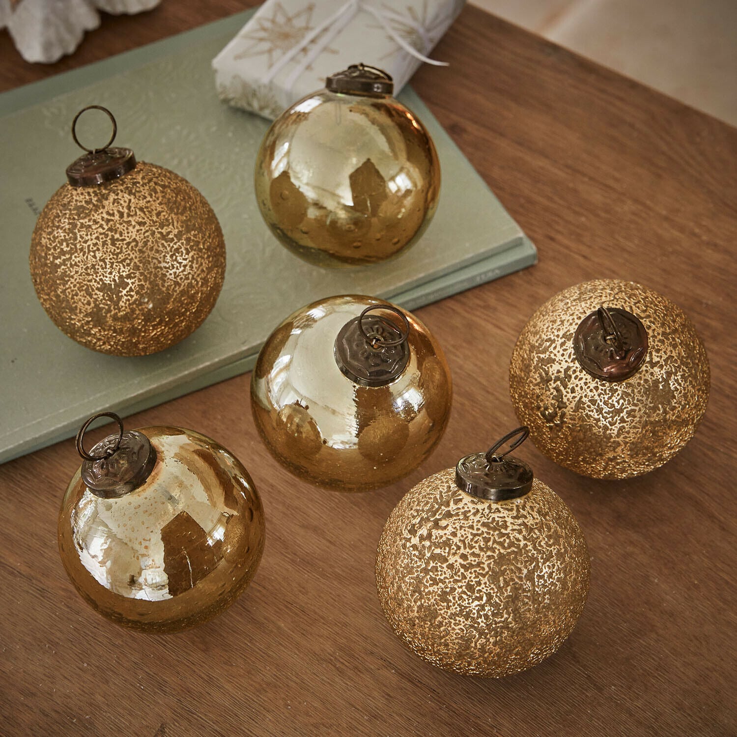Kerstbal set van 6 Fioravino Set van zes gouden glazen kerstballen met verschillende texturen op een houten tafel