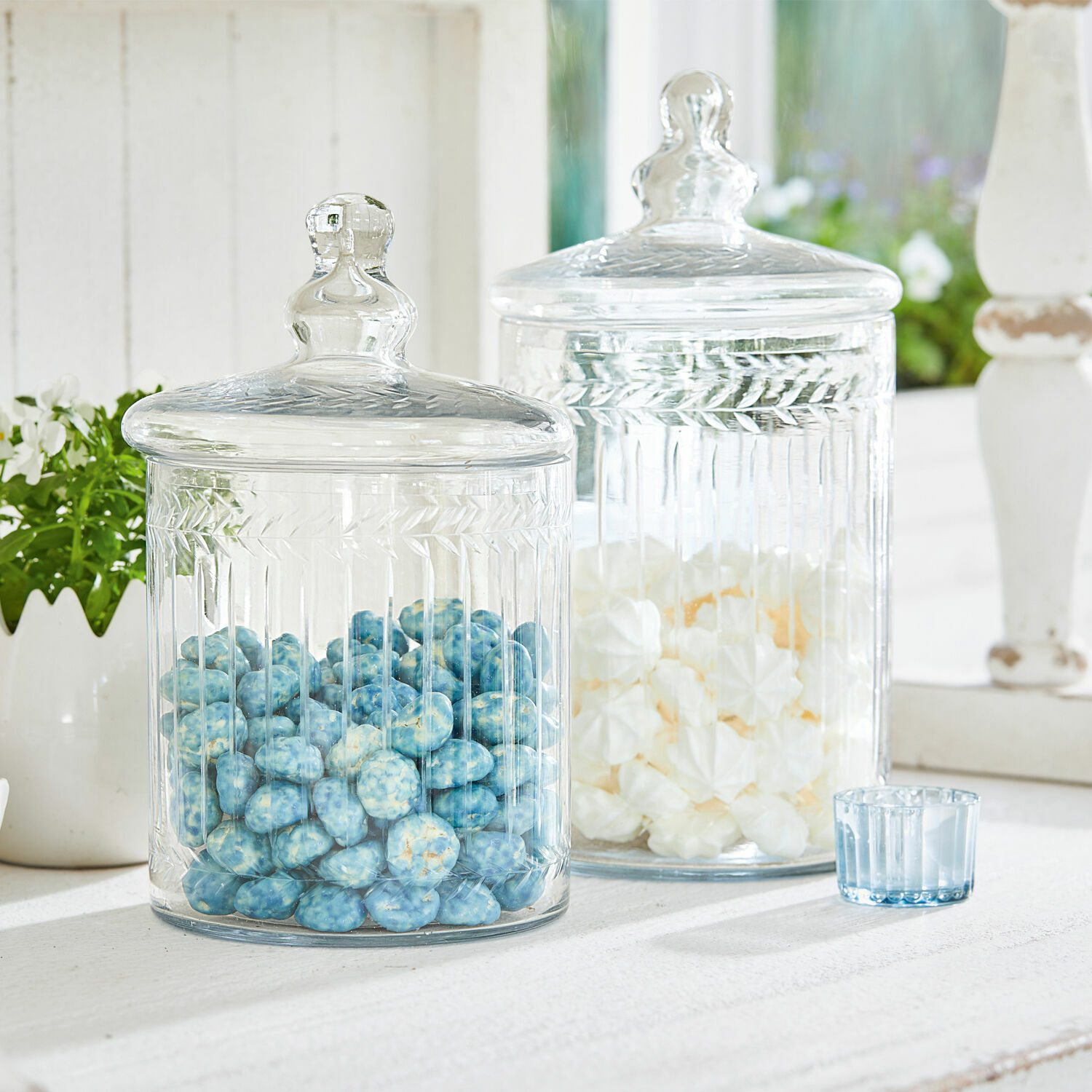 Glazen pot set van 2 Maledisant Transparante glazen potten met deksels gevuld met blauwe en witte snoepjes op een witte tafel