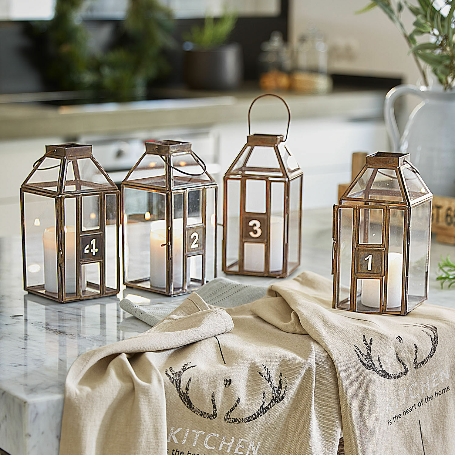 Vier genummerde metalen lantaarns met kaarsen op een marmeren keukenblad