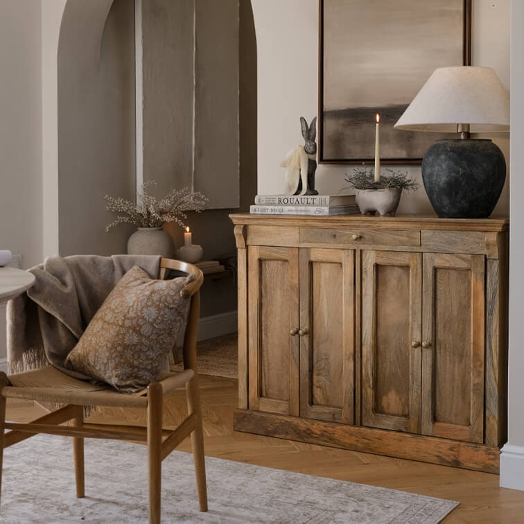 Houten dressoir in natuurlijke kleur met lamp en decoratie in gezellige woonkamer met stoel en kussen
