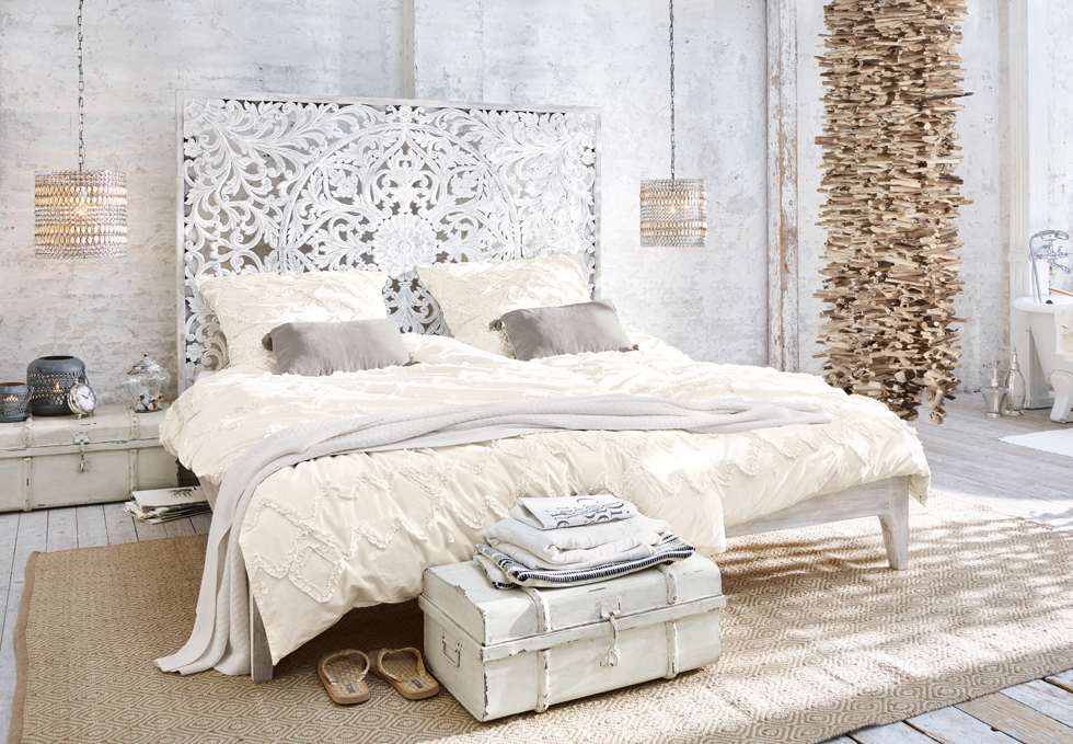 Boho slaapkamer met wit gesneden bed, crèmekleurig beddengoed en natuurlijke houten decoraties