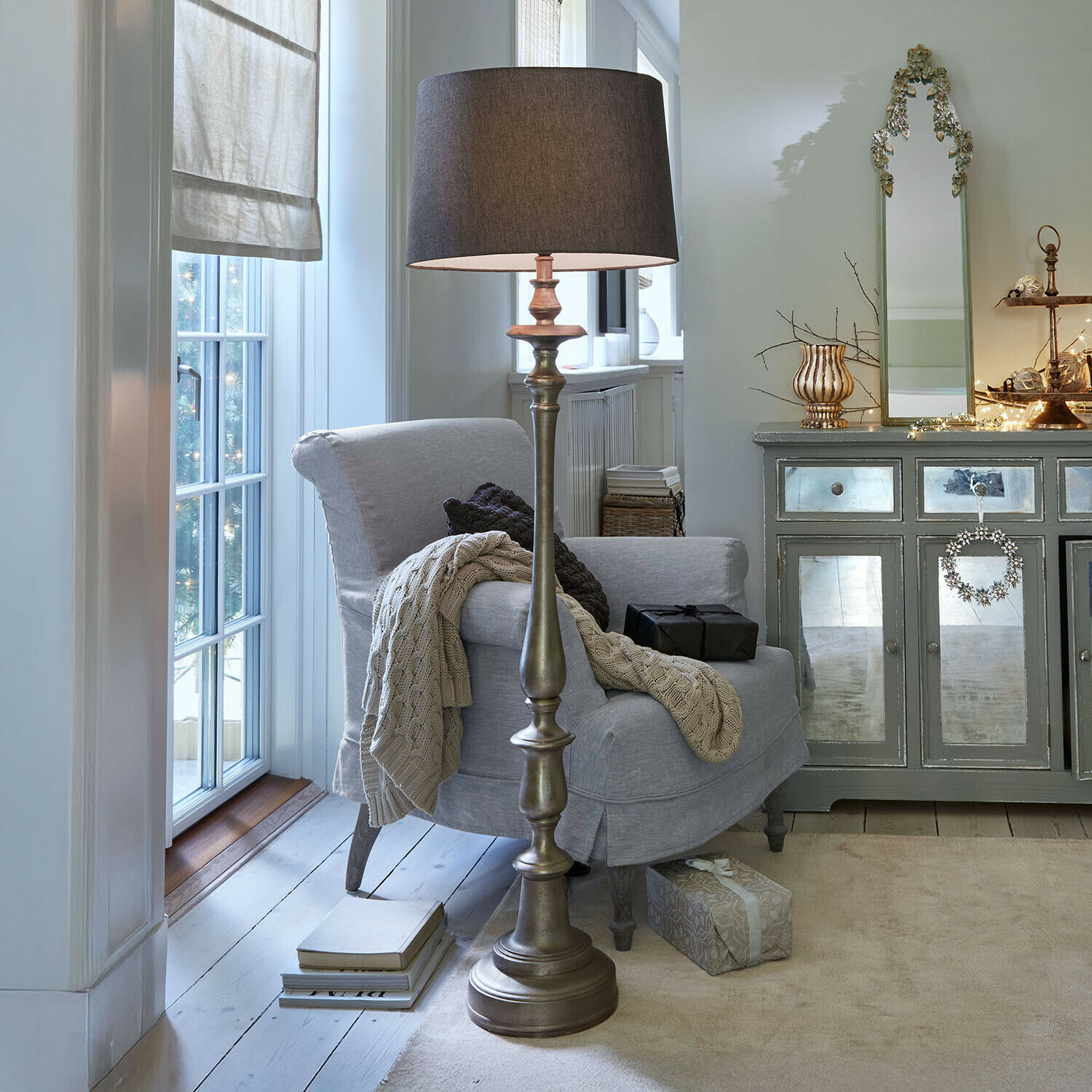 Stijlvolle vloerlamp met metalen voet en donkere kap in een gezellige woonkamer met grijze fauteuil