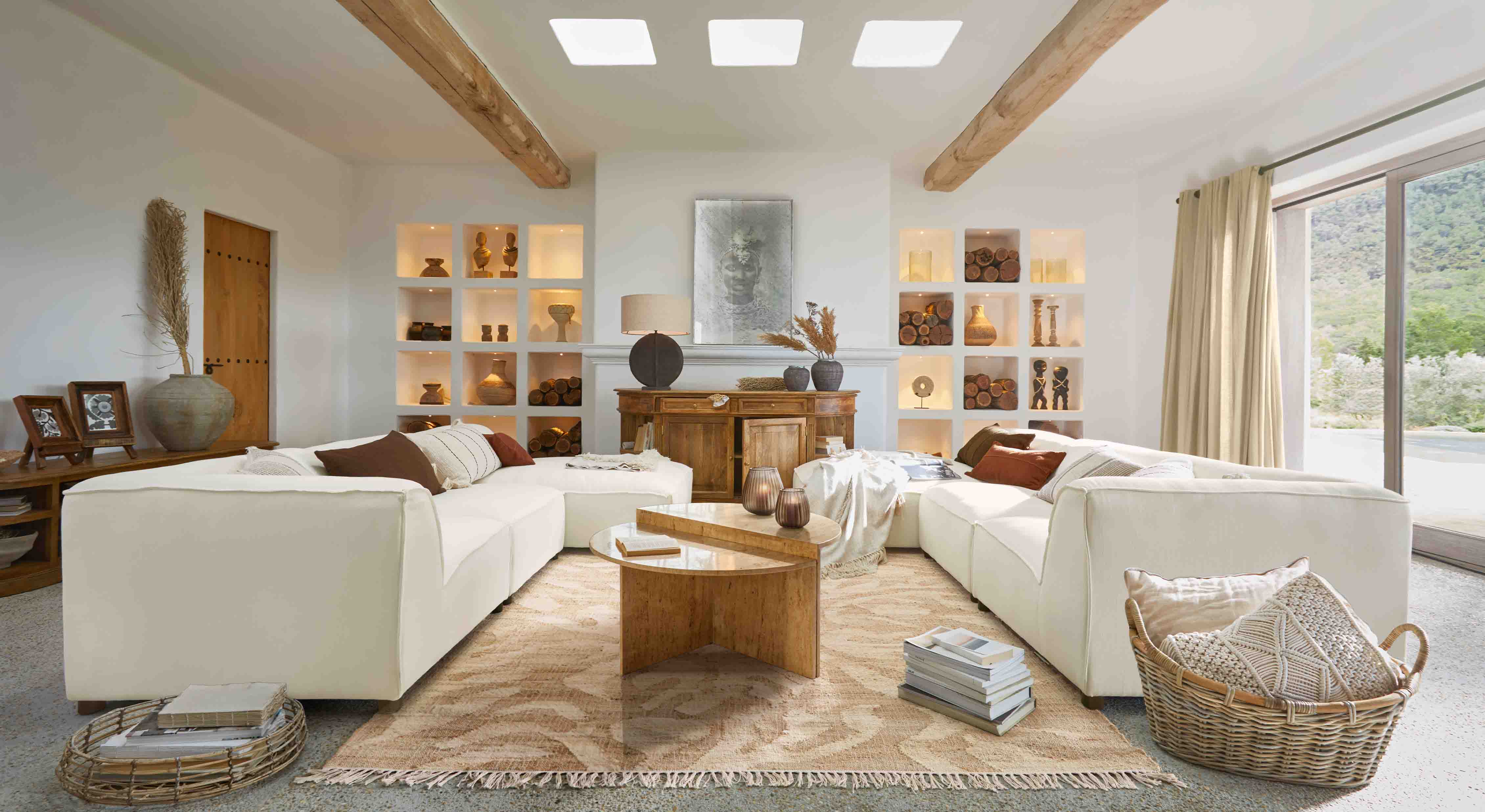 Ruime woonkamer met witte hoekbank, houten salontafel en warme natuurlijke decoraties