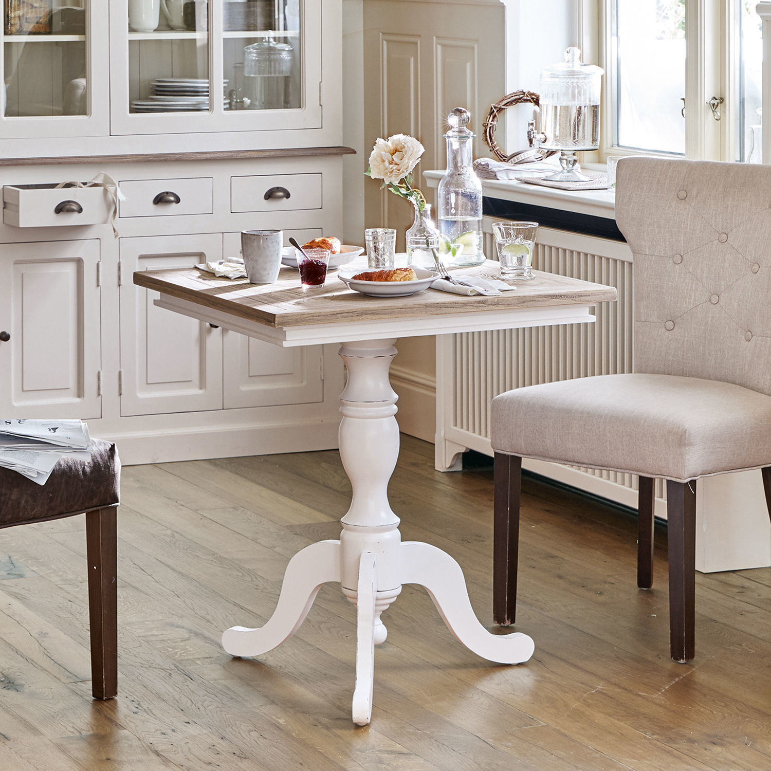 Tafel Kingston Witte houten tafel met sierlijke poot en naturel houten blad in lichte keukenruimte