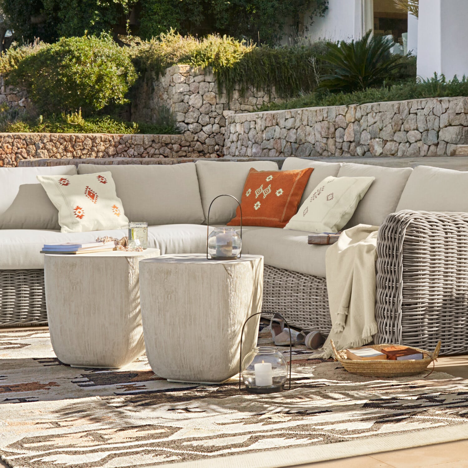 Hoekfauteuil Eravinto Buitenmeubelset met beige rotan bank en twee lichte bijzettafels op terras