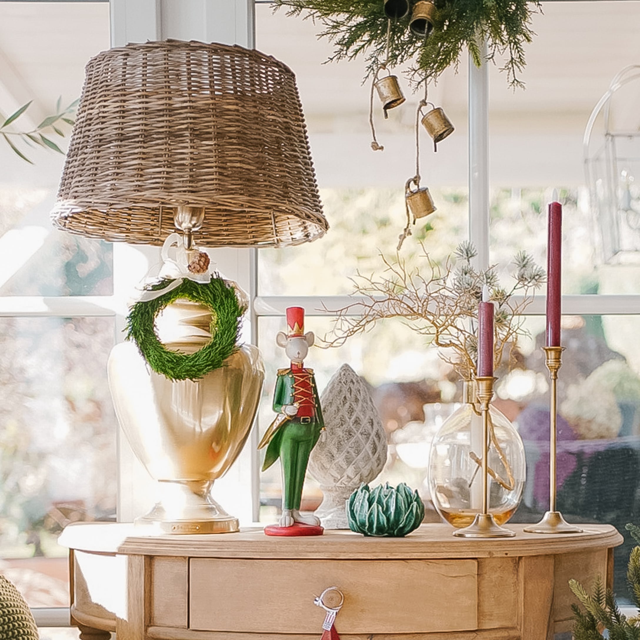 Decoratieve lamp met rieten kap en kerstversiering op lichte houten tafel in interieur