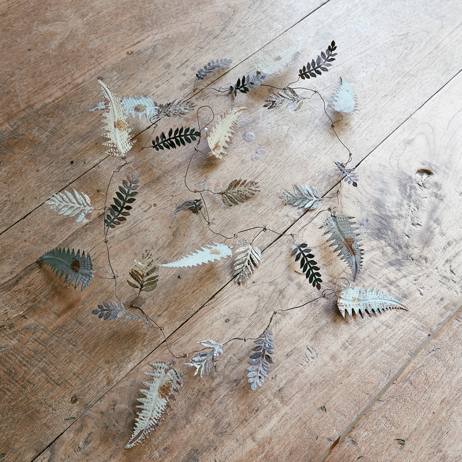 Guirlande Longnor Decoratieve metalen slinger met grijze en witte bladeren op een lichte houten vloer
