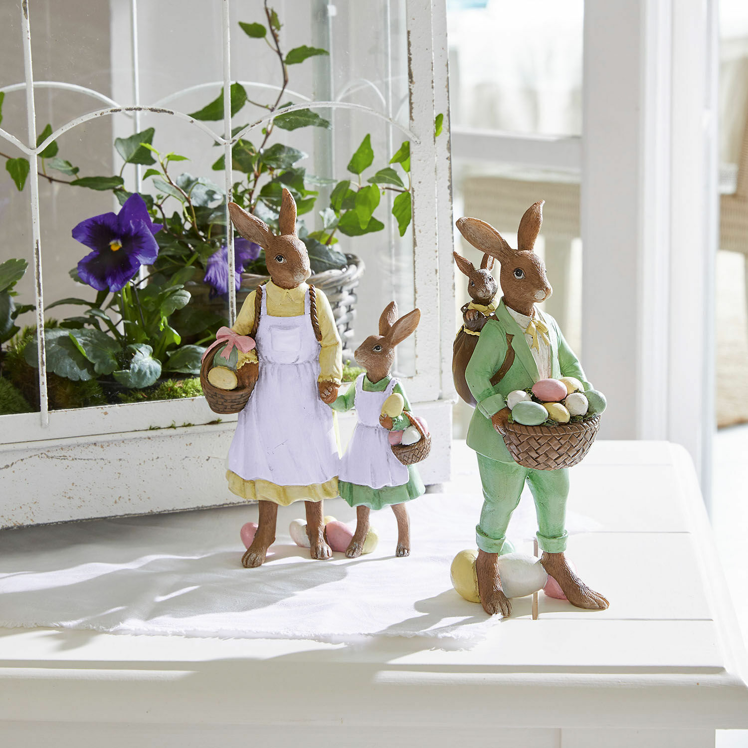 Paashaasfiguren van hars met manden vol pastelkleurige eieren, lente decoratie