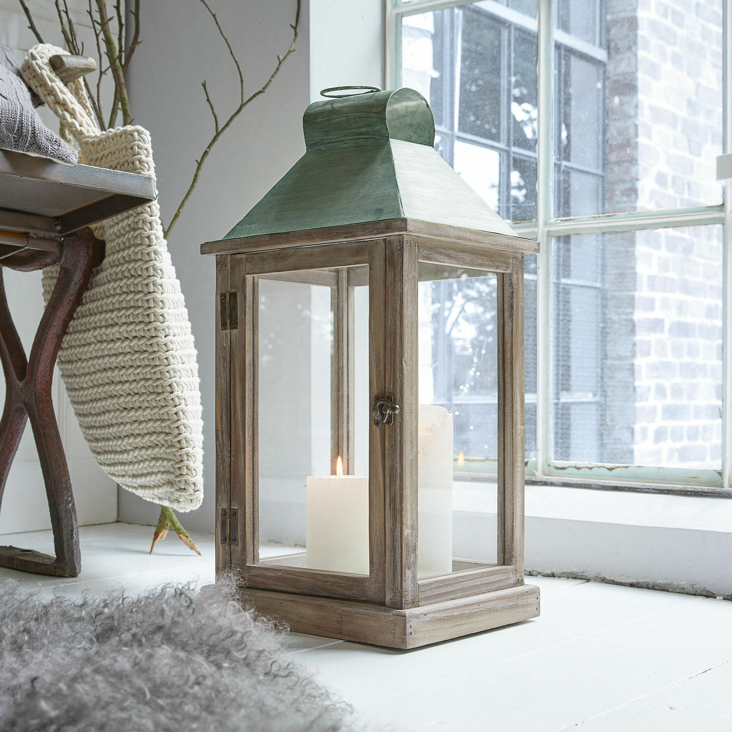 Houten lantaarn met groen metalen dak en witte kaarsen, sfeervolle interieurdecoratie
