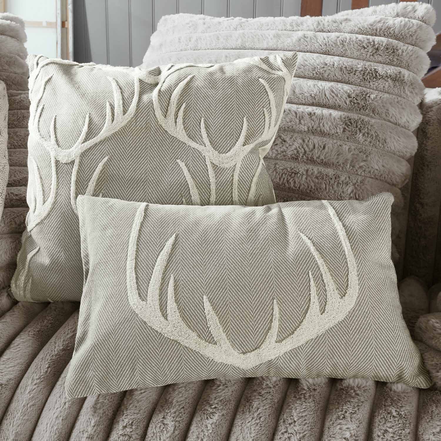 Beige sierkussens met gewei-motief op zachte pluche achtergrond, woontextiel voor woonkamer