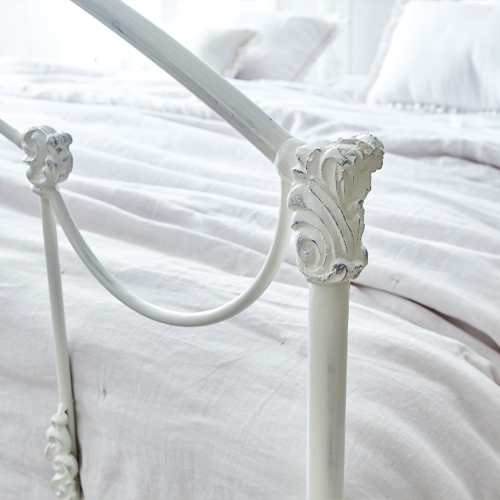Wit metalen Canefield bed met decoratieve details en lichte beddengoed