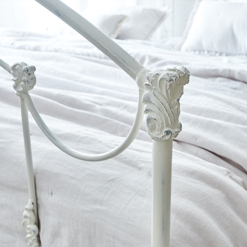 Wit metalen Canefield bed met decoratieve details en lichte beddengoed
