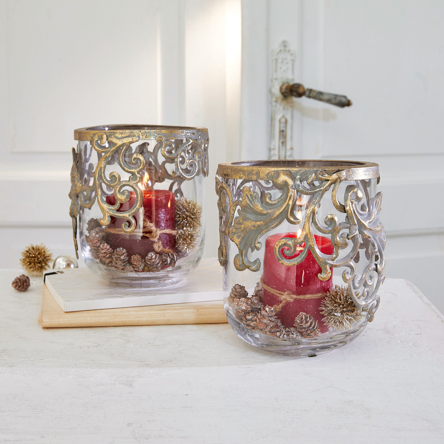 Glazen windlichten met rode kaarsen en gouden versieringen, feestelijke tafeldecoratie