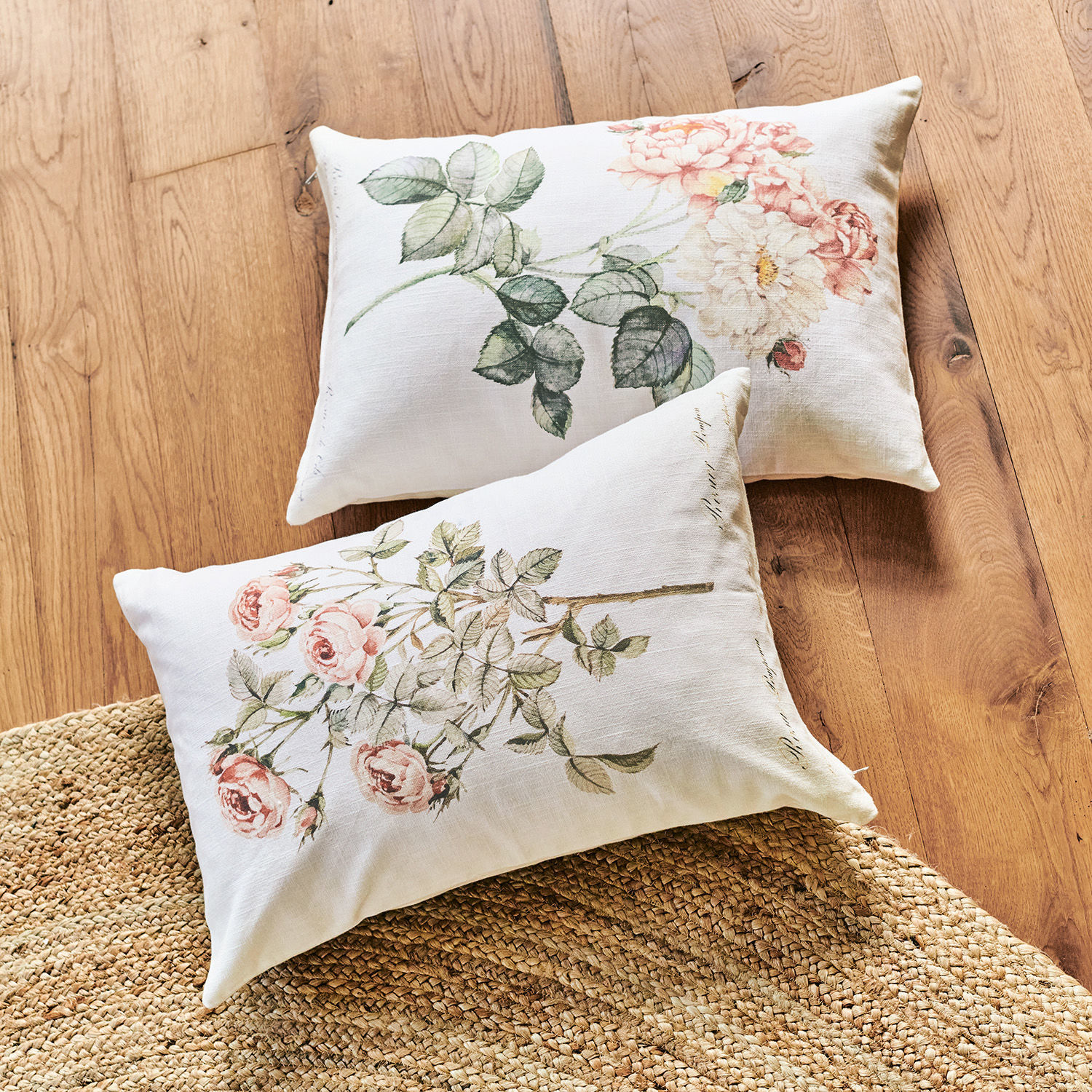 Kussenhoes set van 2 Girona Twee linnen kussens met pastelbloemenprint op een lichte houten vloer