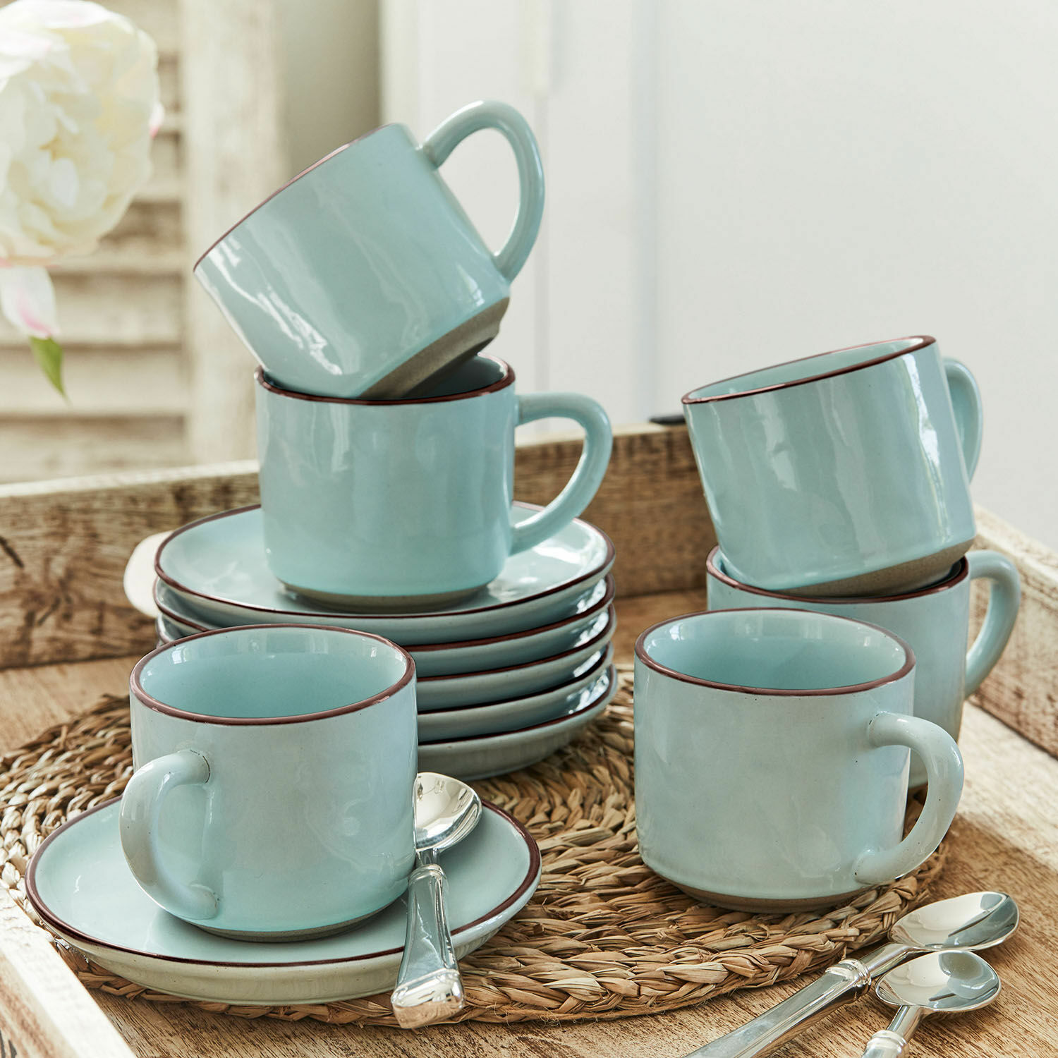 Kopje en schoteltje set van 6 Biarré Set lichtblauwe keramische kopjes met schotels en lepels op een gevlochten onderzetter
