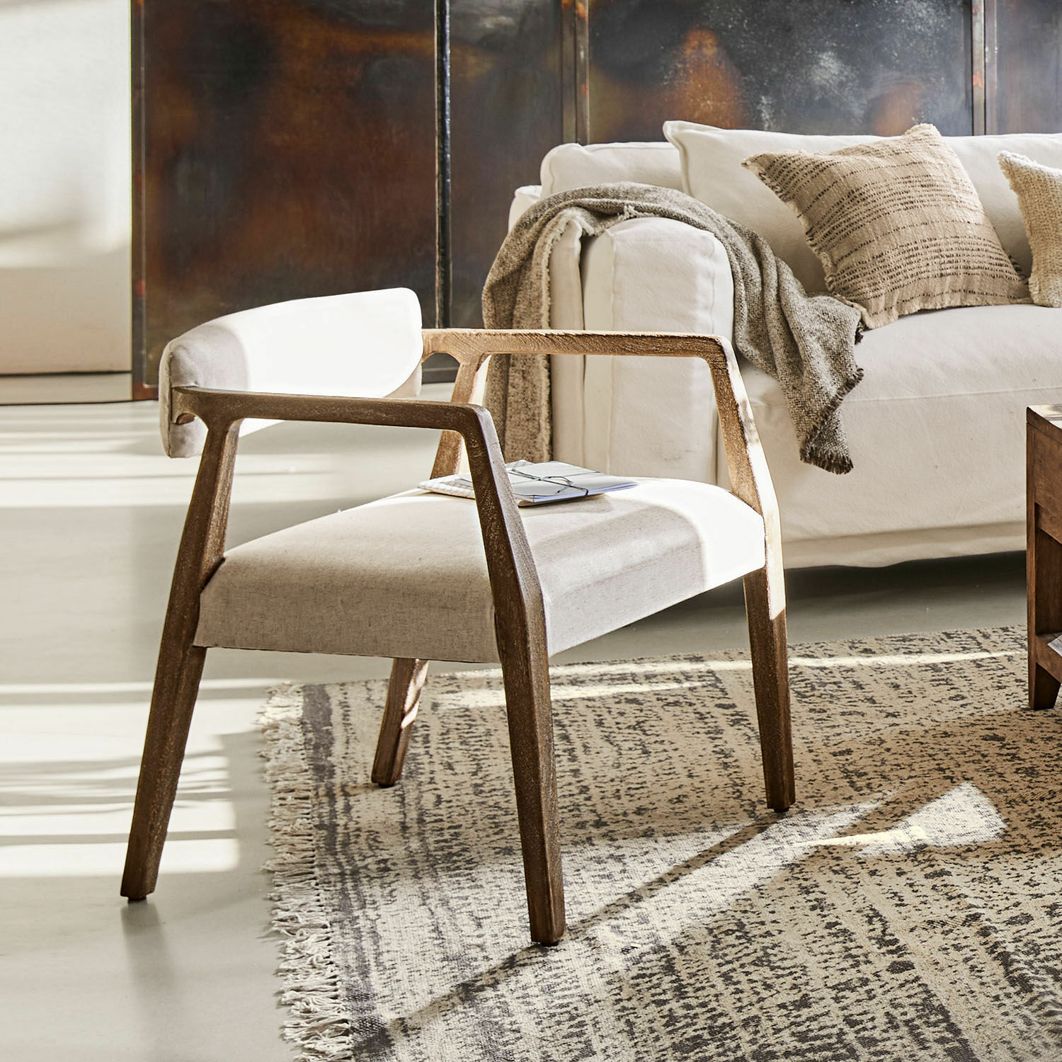 Moderne stoel met houten frame en lichte stofbekleding op tapijt in woonkamer