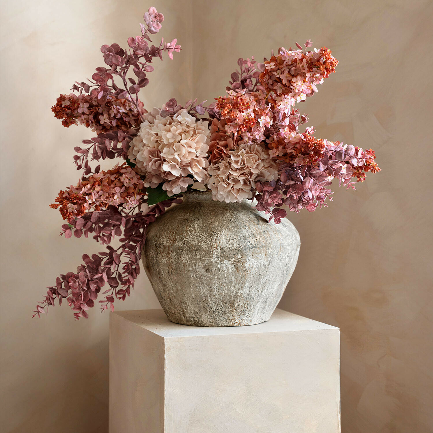 Rustieke stenen vaas met roze en beige decoratieve bloemen voor interieurdecoratie