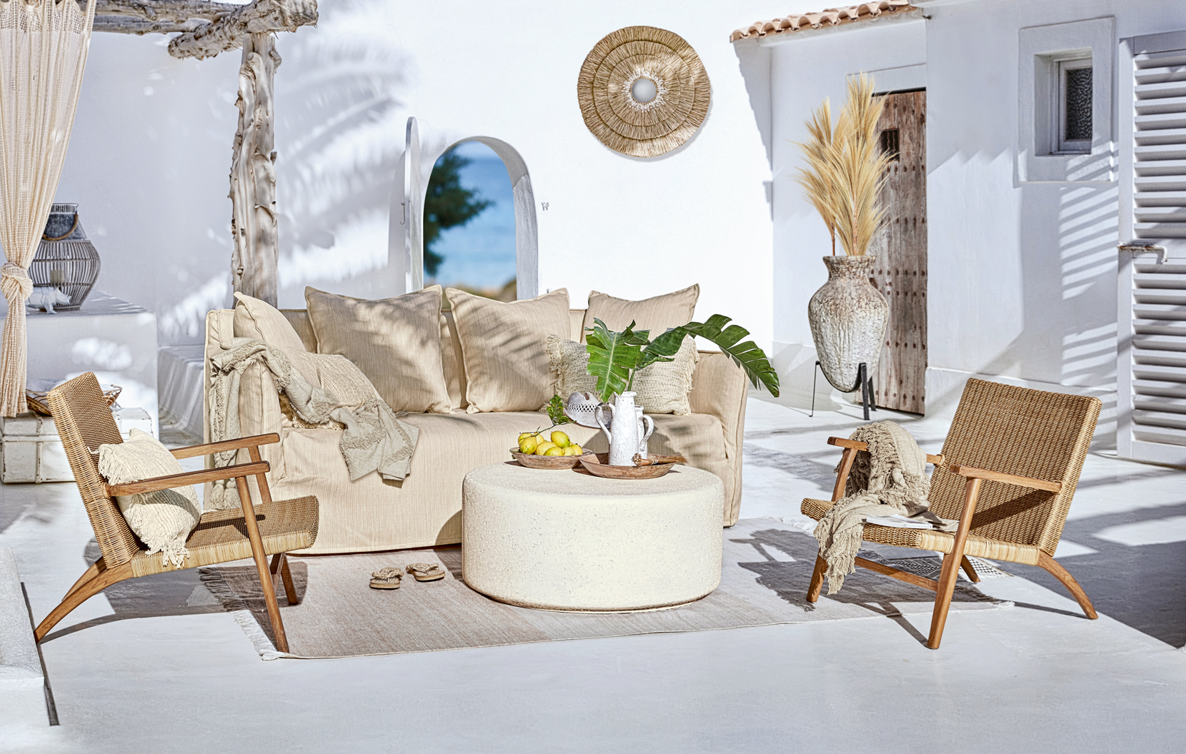 Gezellige boho tuinmeubels met beige bank en rotan stoelen op zonnig terras