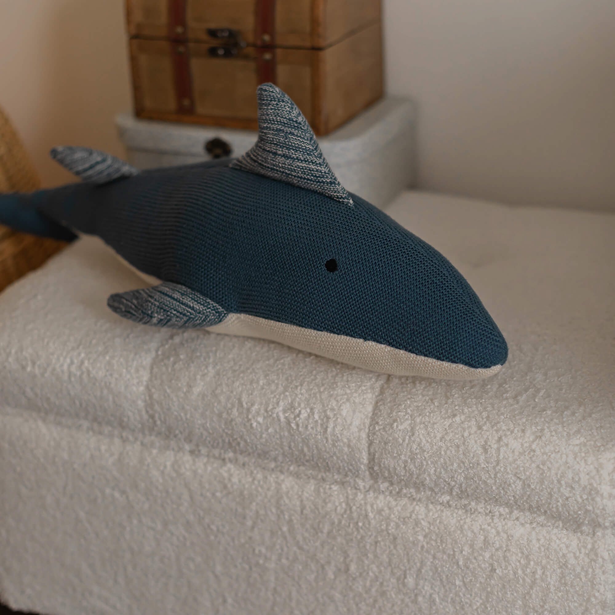 Marineblauw gebreid kussen in haai-vorm op zachte witte stof, kinderkamerdecoratie