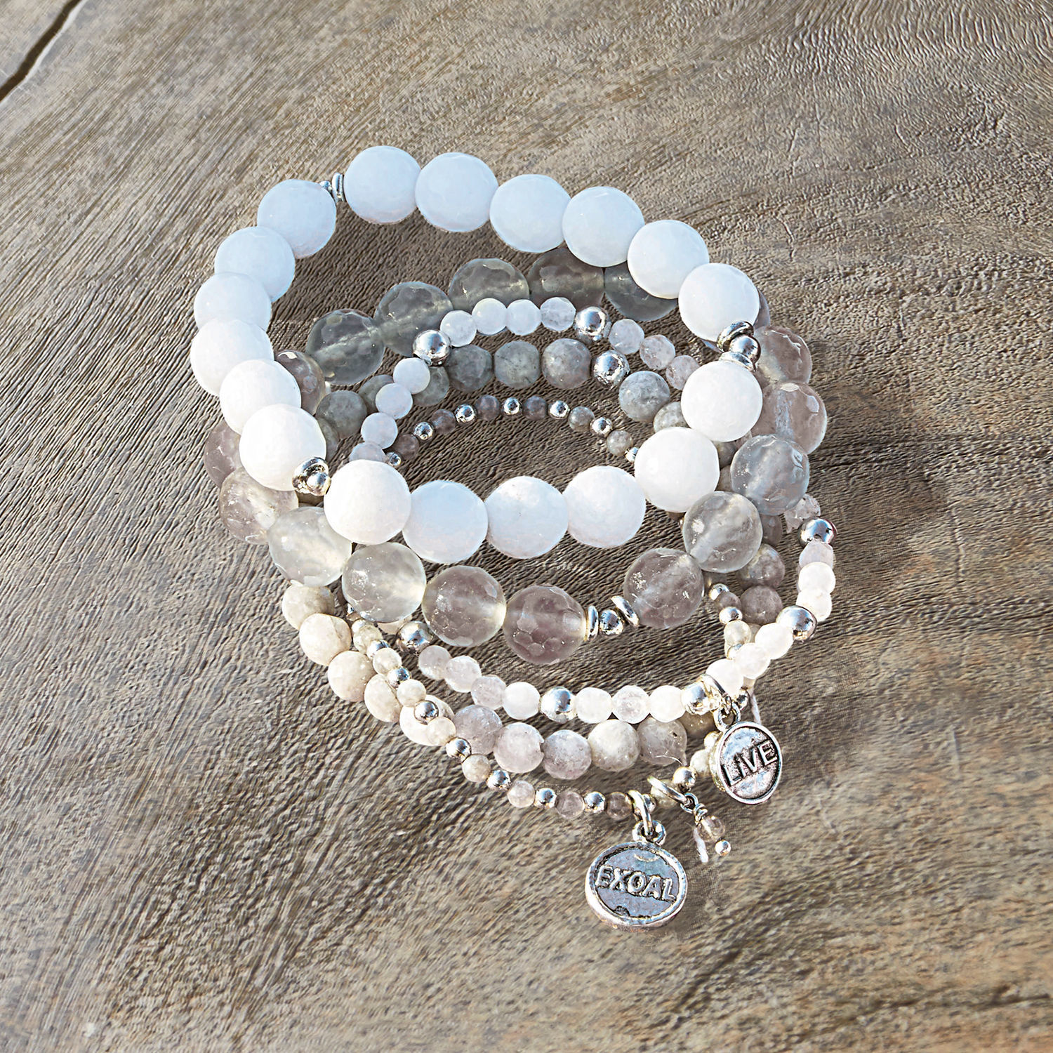 Armband set van 5 Chaim Set armbanden met witte en grijze stenen en metalen bedels op houten achtergrond