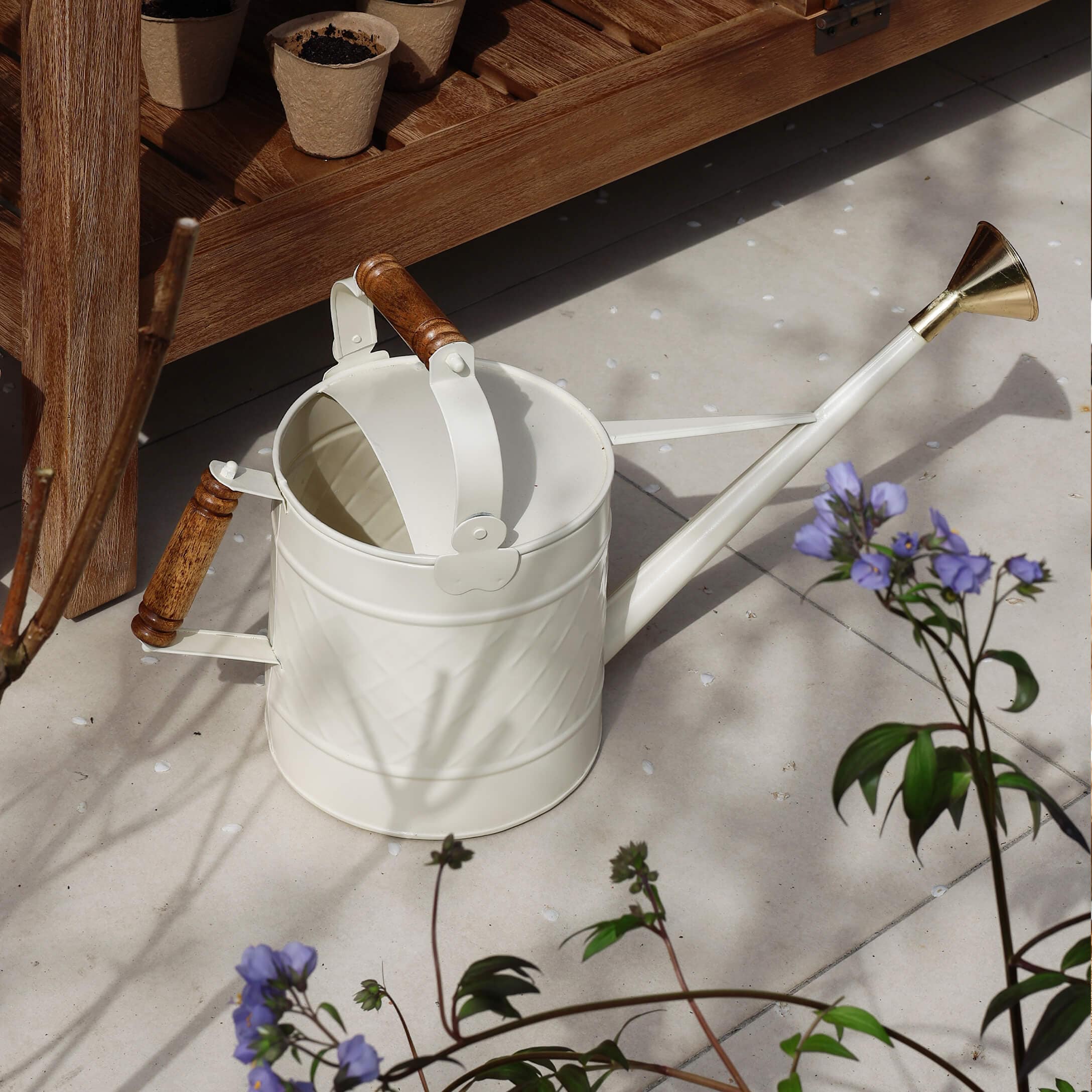 Witte metalen gieter met houten handvatten en messing sproeikop voor tuinieren