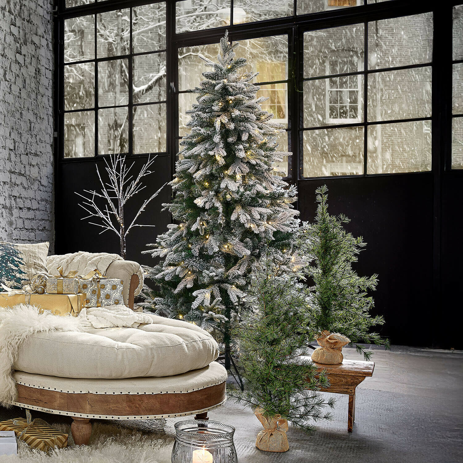 Kerstboom Norila Kunstkerstboom met sneeuw en lichtjes in moderne kamer met beige bank en cadeaus