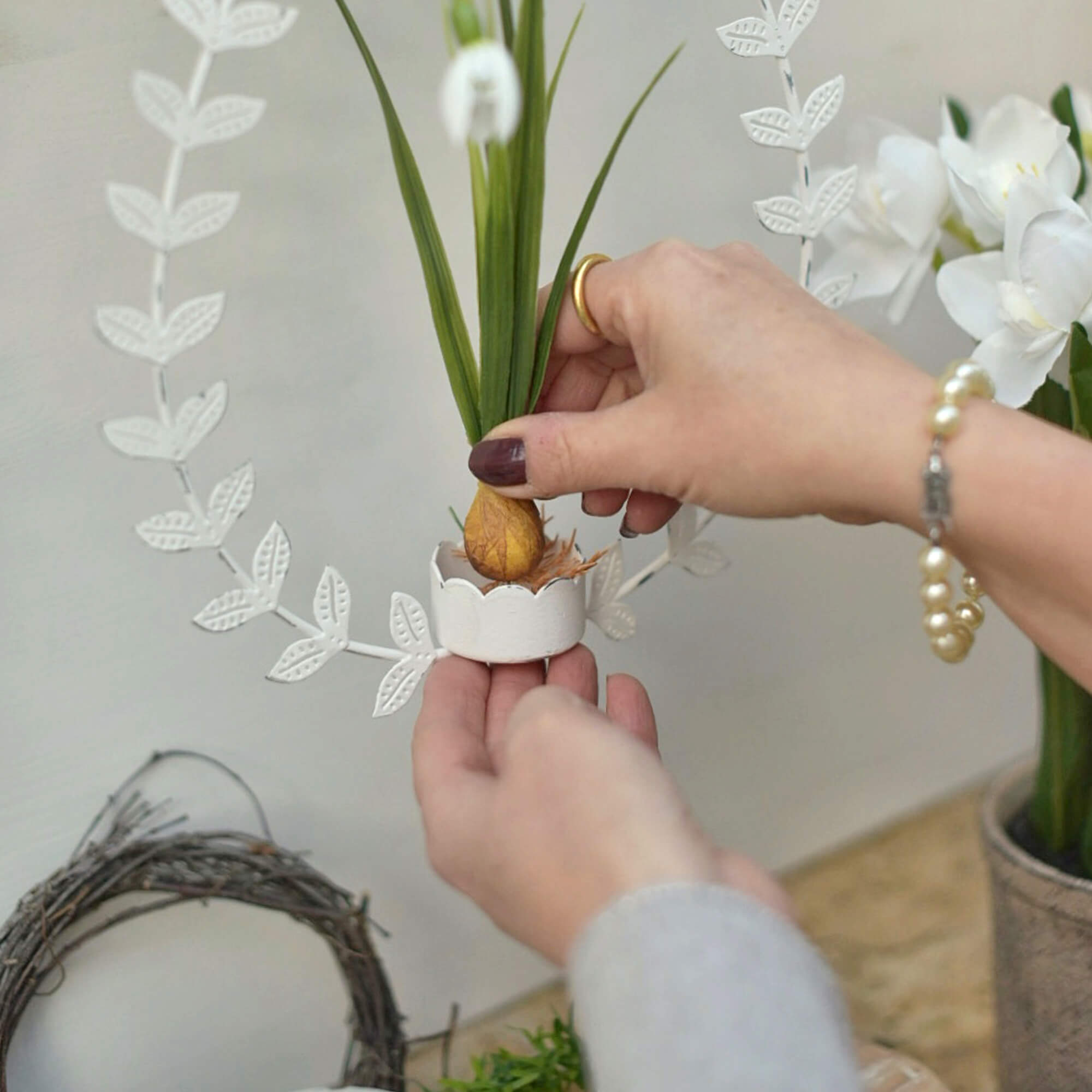 Witte metalen krans met bladeren en kunstplant in natuurlijke paasdecoratiestijl