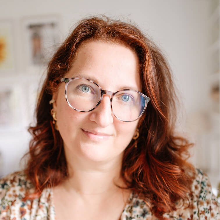 Portret van vrouw met rood haar en bril in lichte, wazige binnenruimte