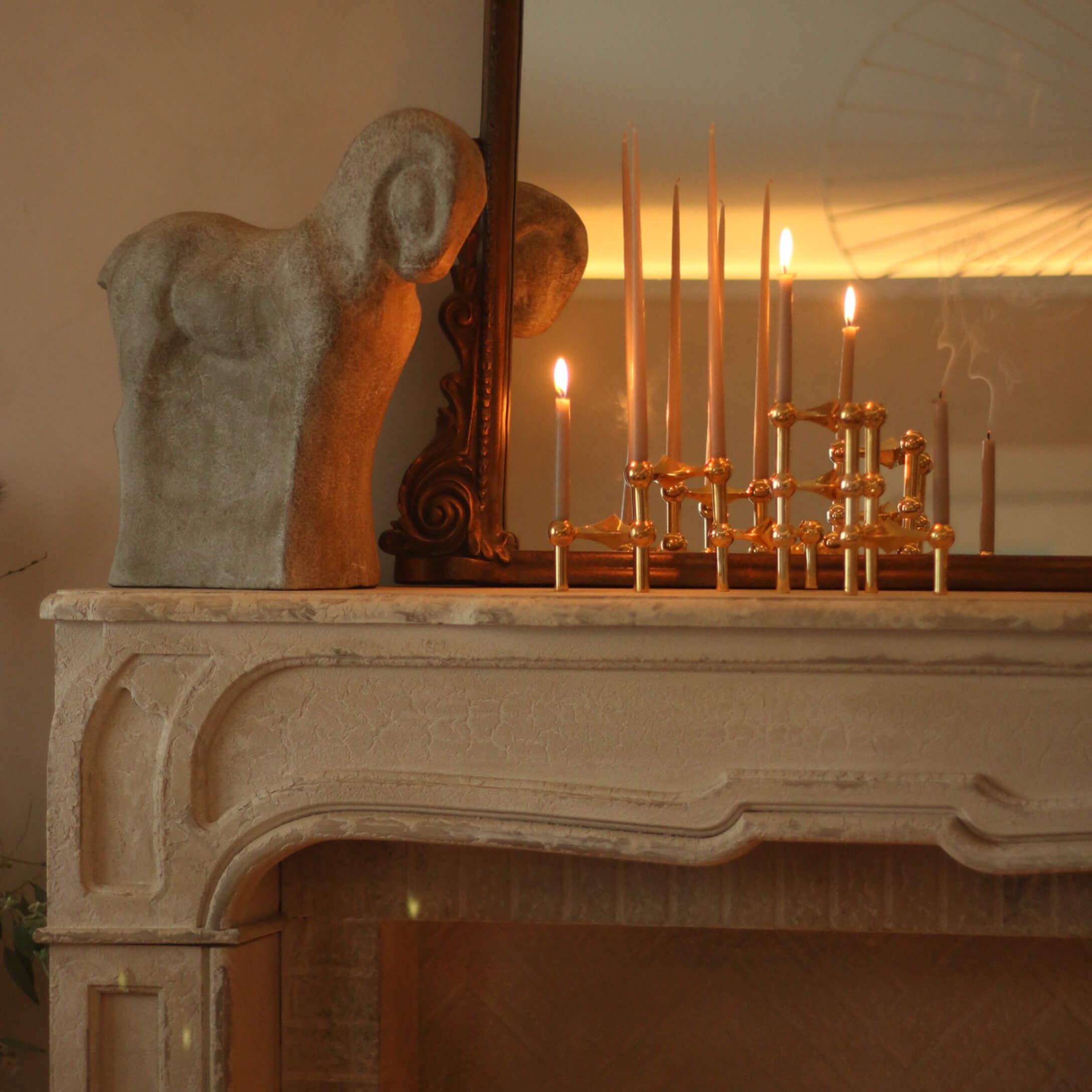 Decoratief stenen rambeeld op schoorsteenmantel met messing kandelaar en brandende kaarsen