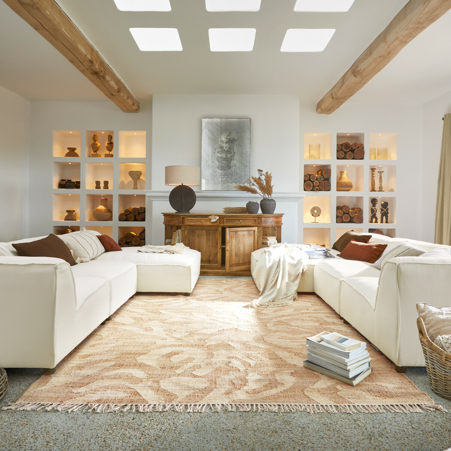 Gezellige woonkamer met witte bank, houten dressoir en houten decoraties op beige vloerkleed