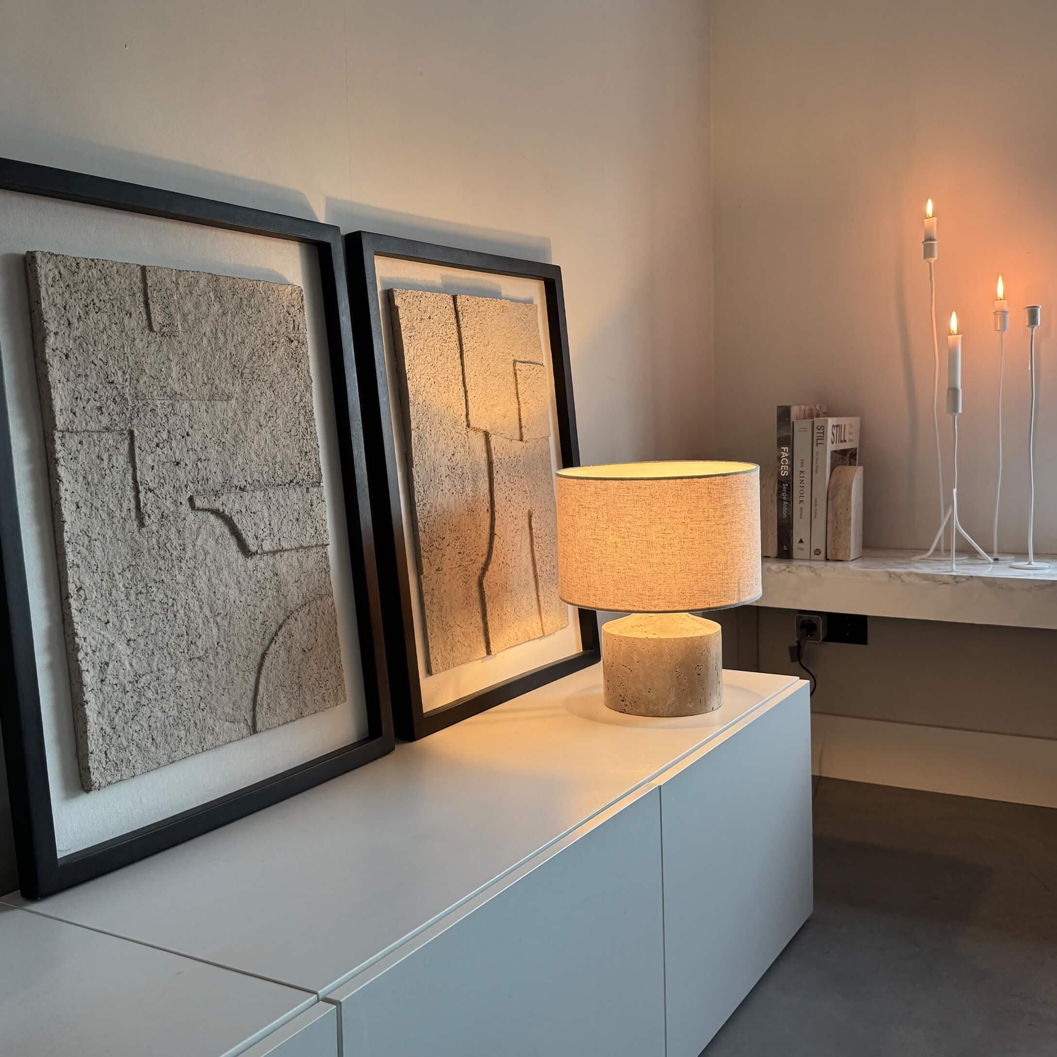 Moderne tafellamp met beige kap en stenen voet op witte kast met textuur muurdecoratie