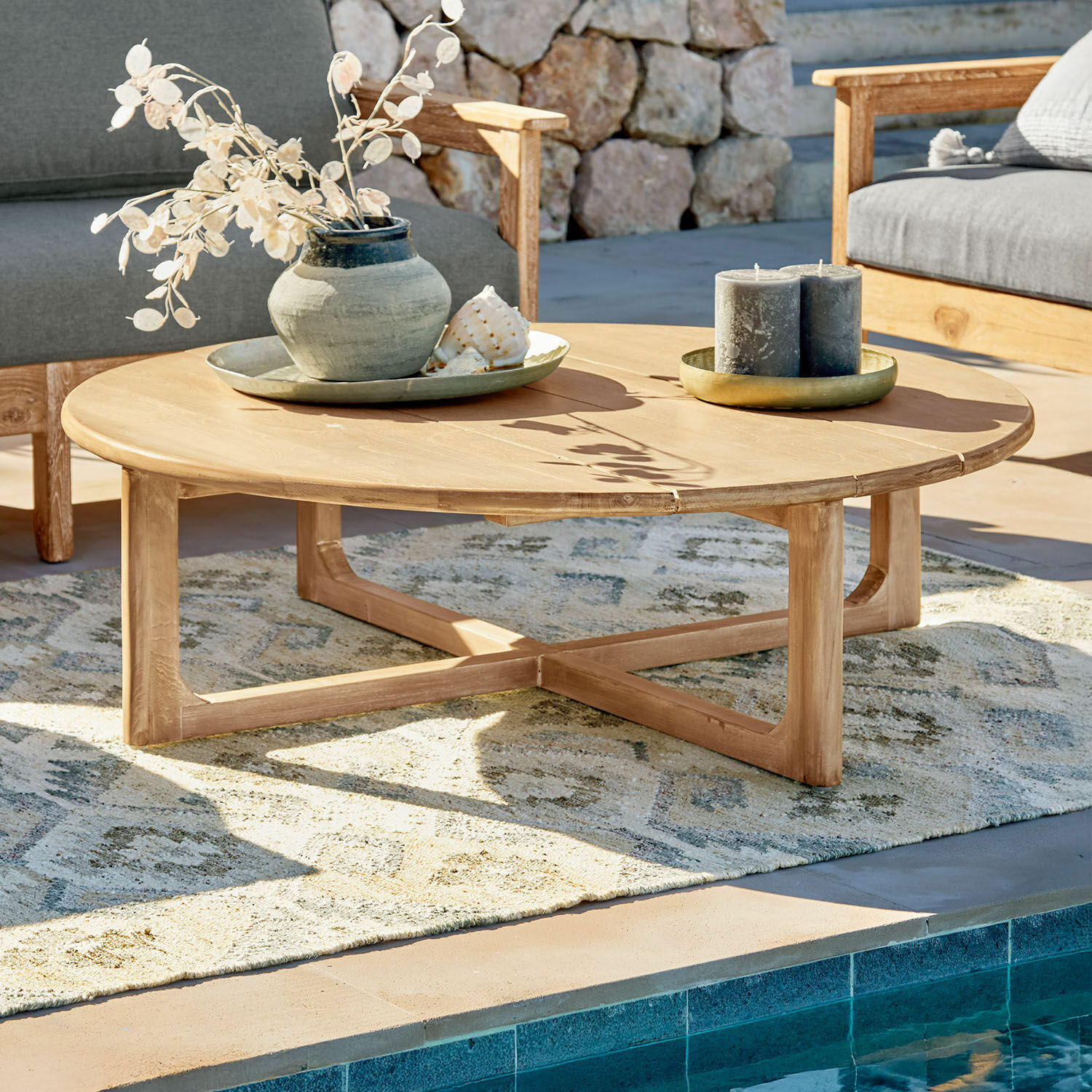 Salontafel Tewksbury Ronde salontafel van natuurlijk teakhout op terras bij zwembad met decoraties
