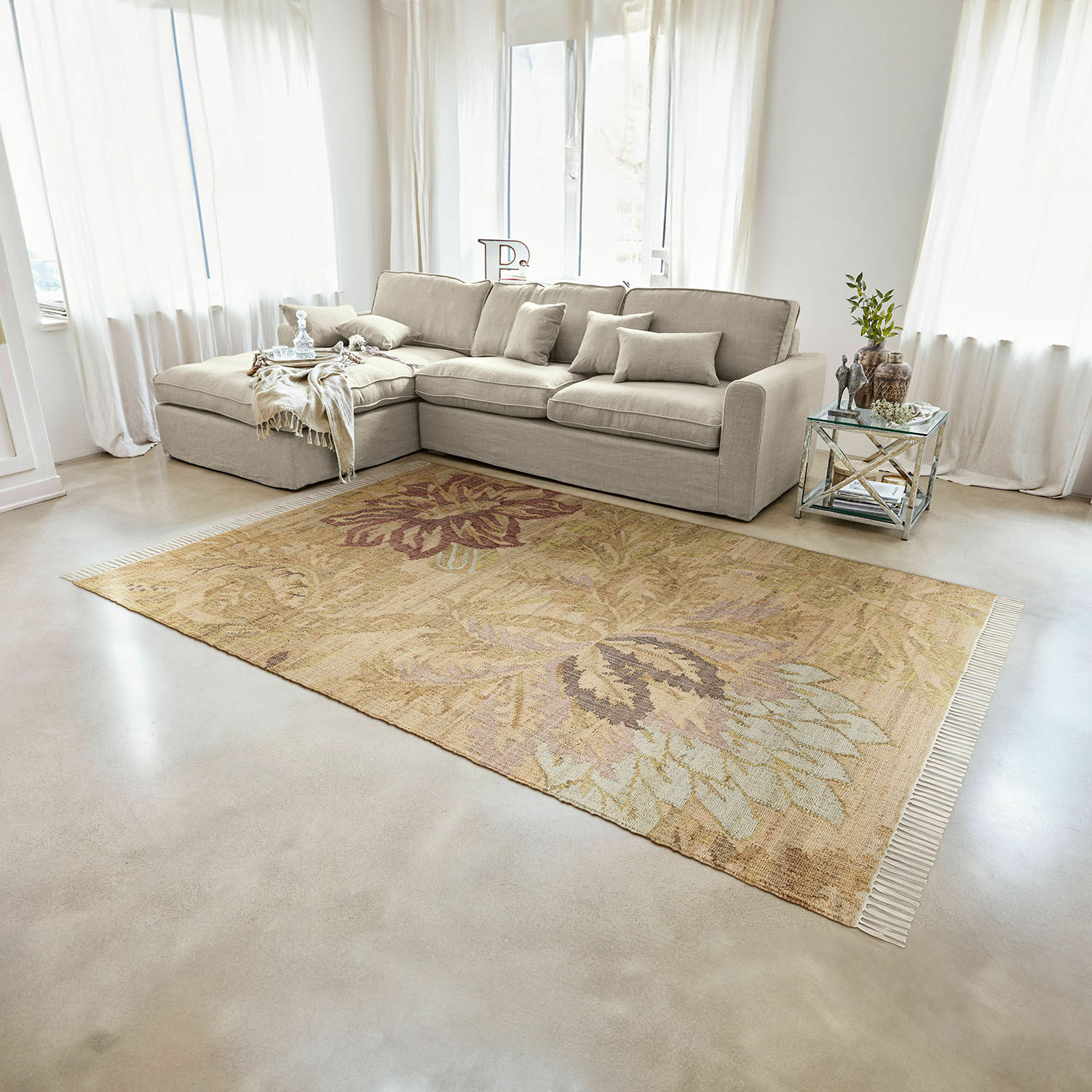 Beige vloerkleed met bloemmotief op lichte vloer in moderne woonkamer met bank