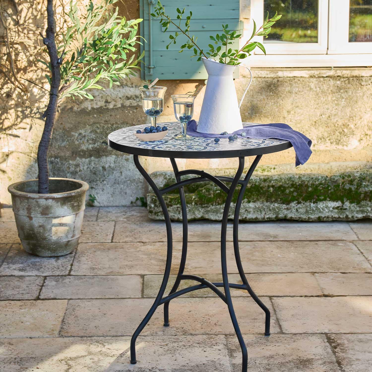 Ronde tuintafel met metalen poten en blauw-wit mozaïekblad voor buiten