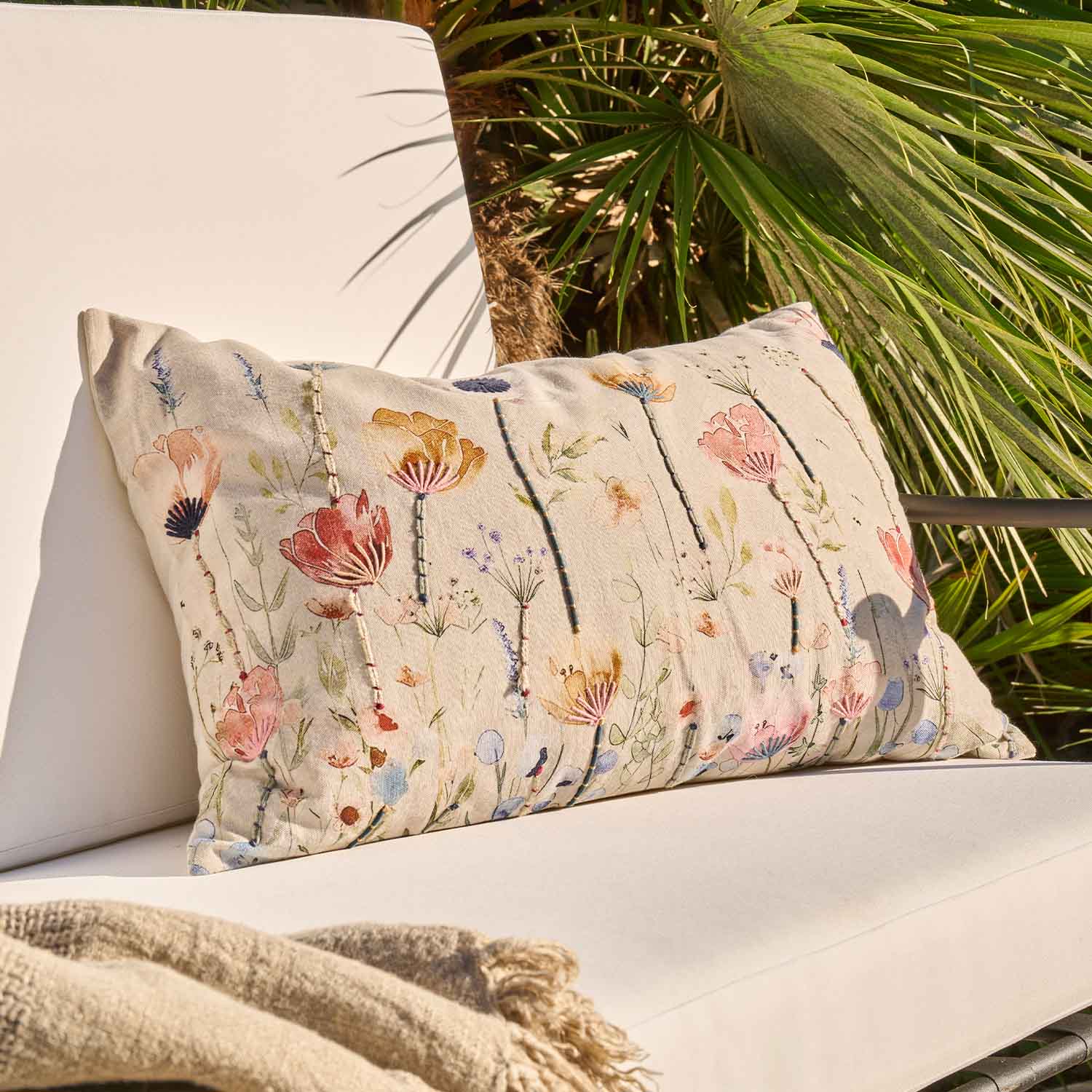 Beige sierkussen met geborduurd bloemenpatroon op lichte stof, geschikt voor woonkamer en tuin