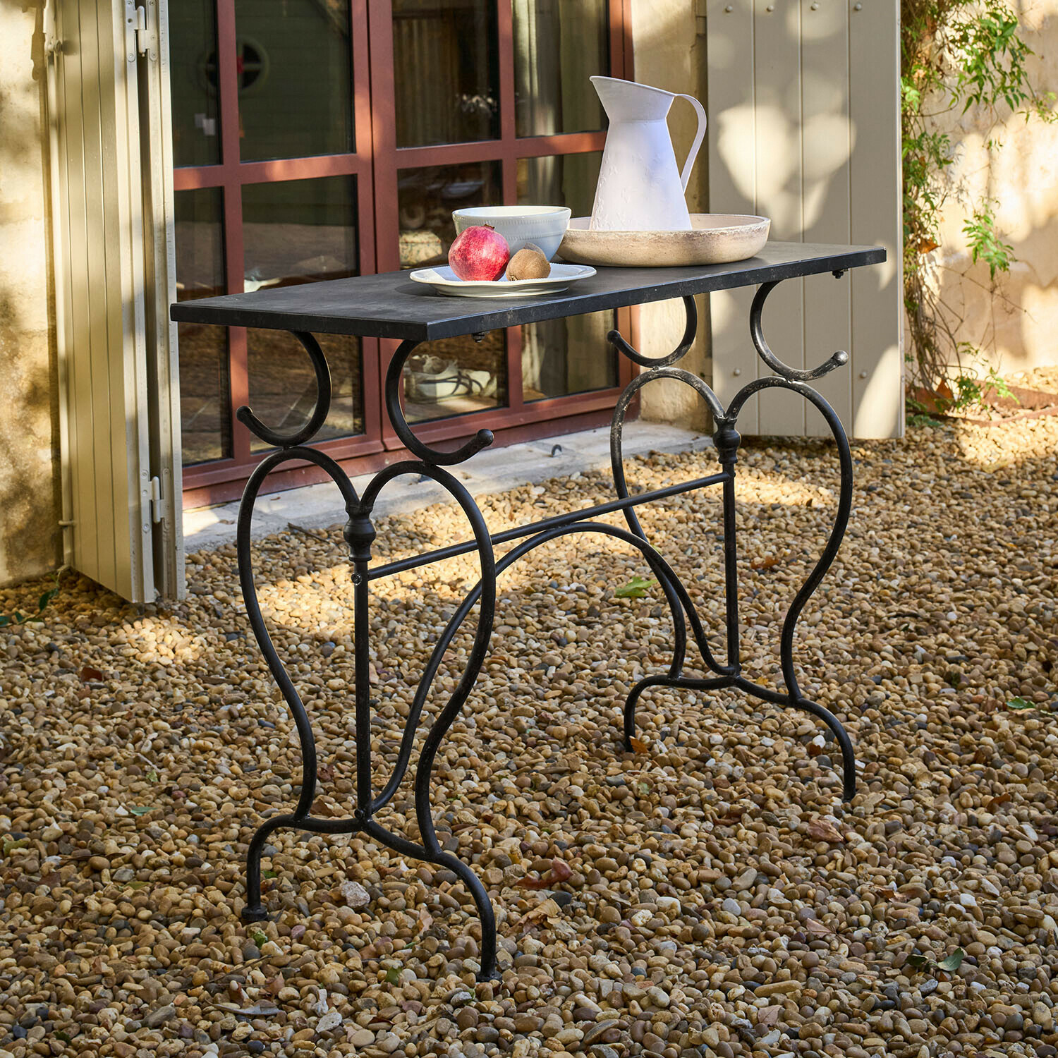 Tuin tafel van zwart metaal met rechthoekig blad op grind met decoraties