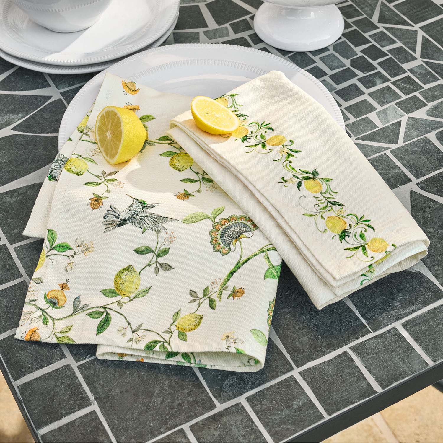 Linnen servetten met citroen- en vogelmotief op grijze stenen tafel, tafeldecoratie