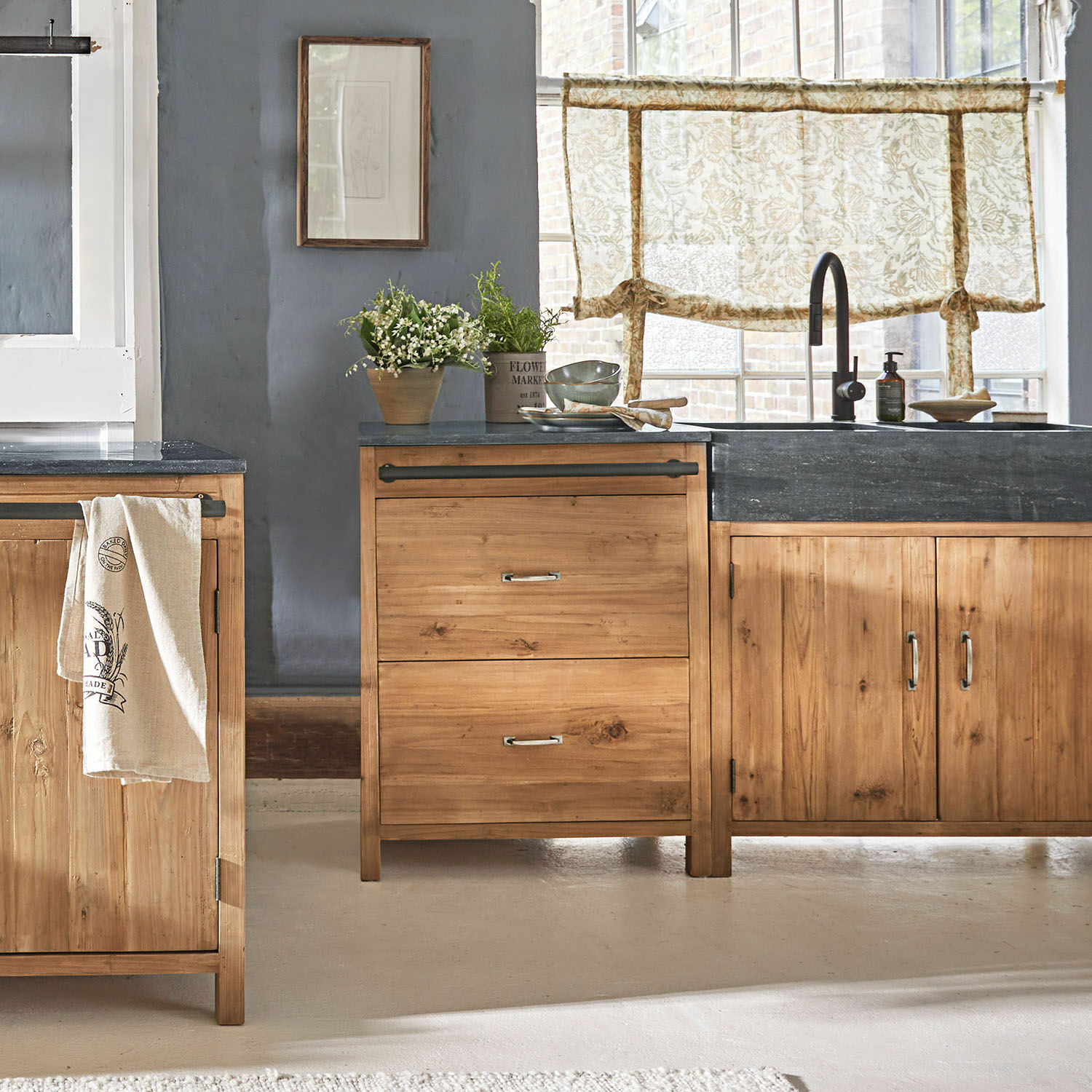 Basiskast Sunnybrook Keuken met houten kasten en zwart werkblad, planten en gordijnen met bloemenpatroon