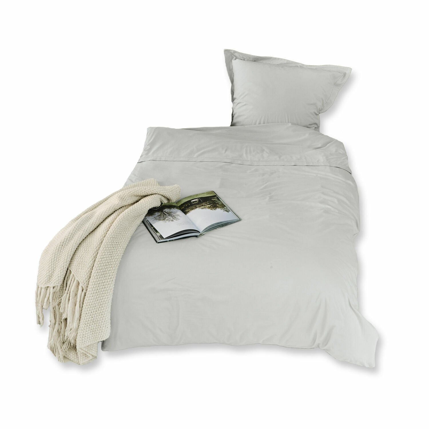 Grijze Grosseto katoenen beddengoed met crème gebreid deken en open boek op bed