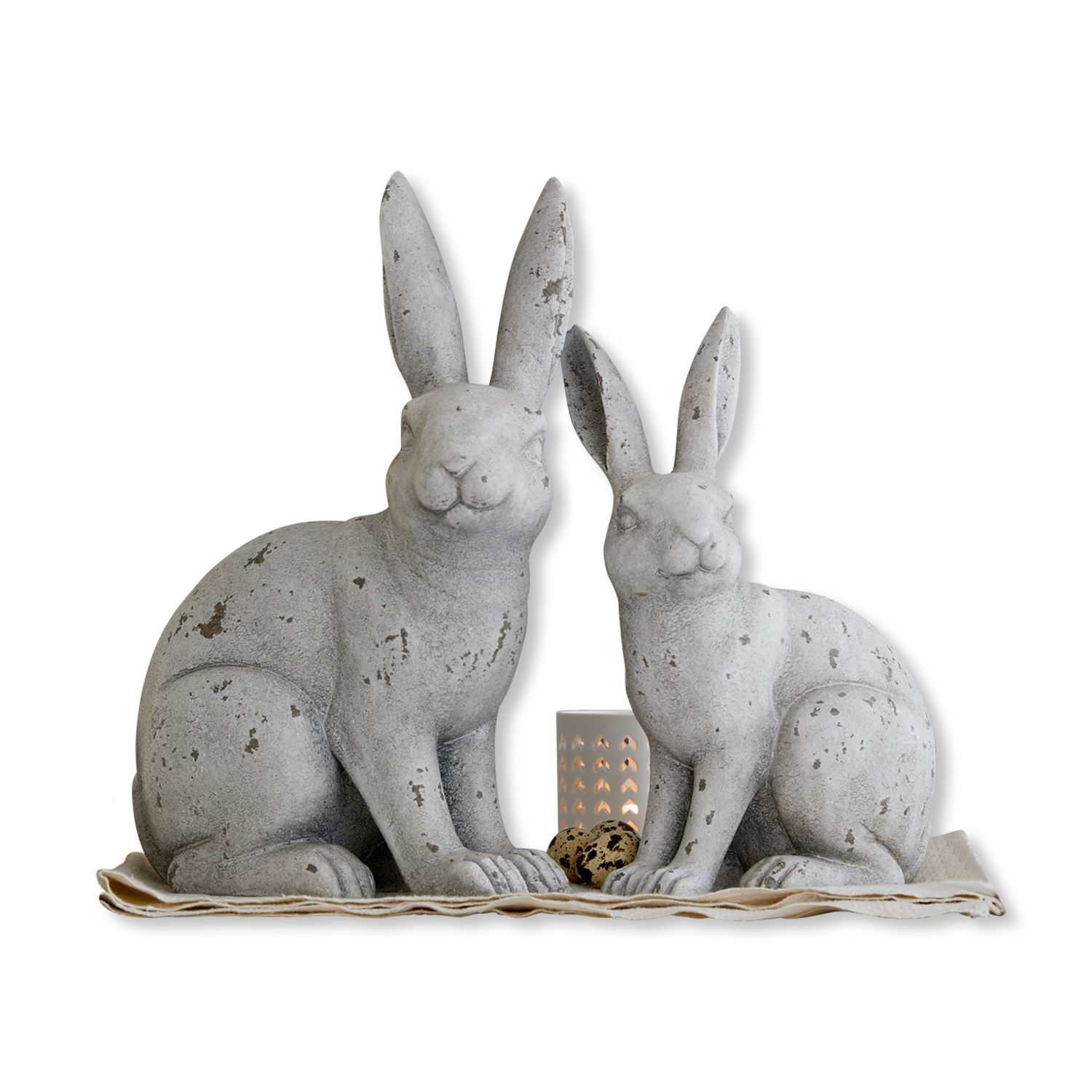 Decoratieve grijze konijnenfiguren van beton op stof met kaarsenhouder en decoratieve eieren