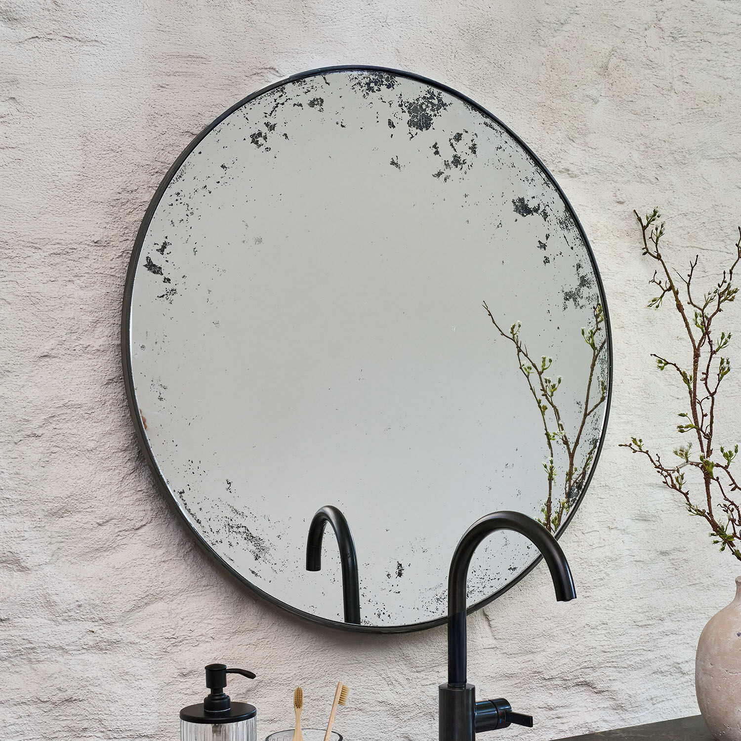 Ronde spiegel met verouderde zwarte metalen lijst tegen witte muur, badkamerdecoratie