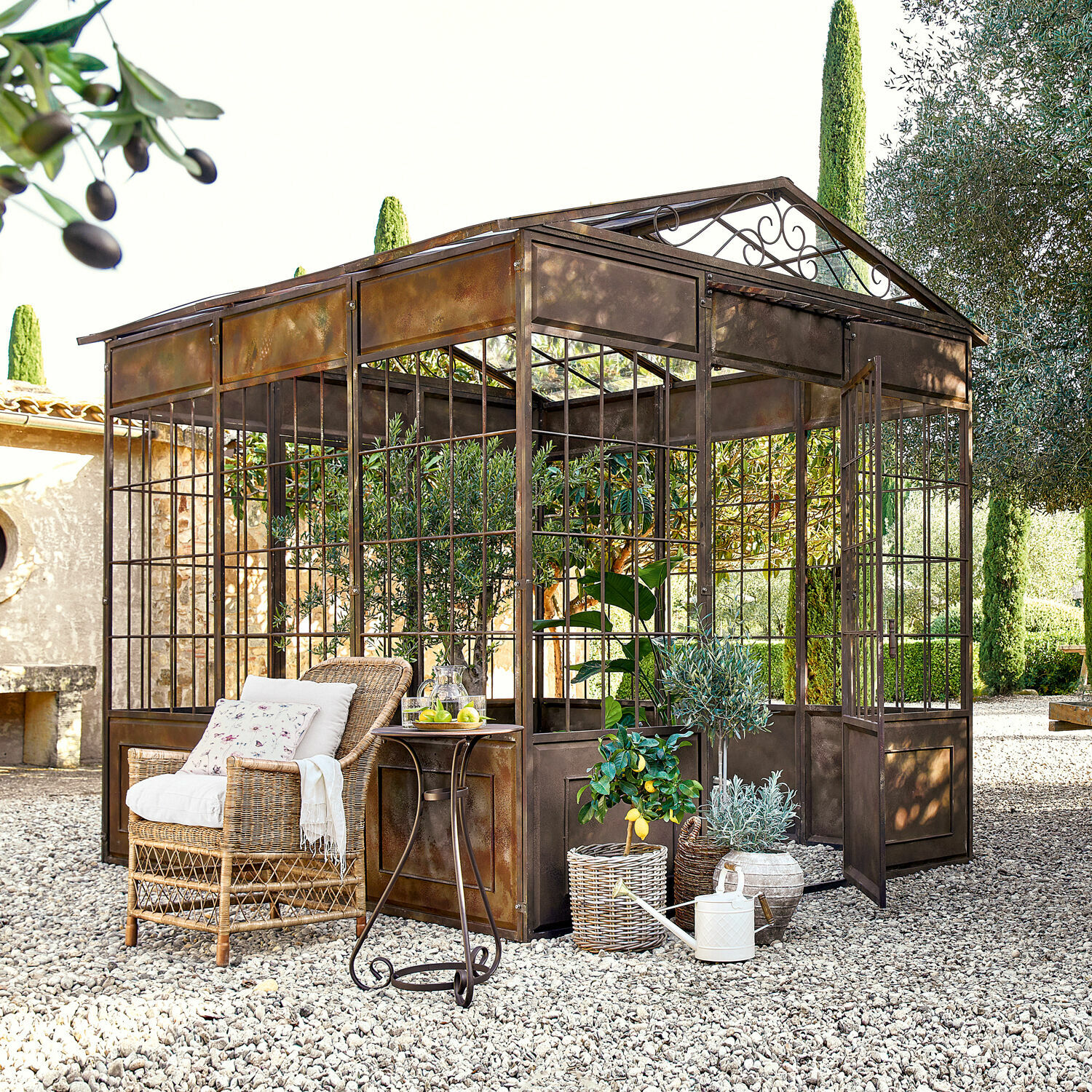 Paviljoen Essone Rustieke metalen orangerie op grind met rotan stoel en decoratieve planten in tuin