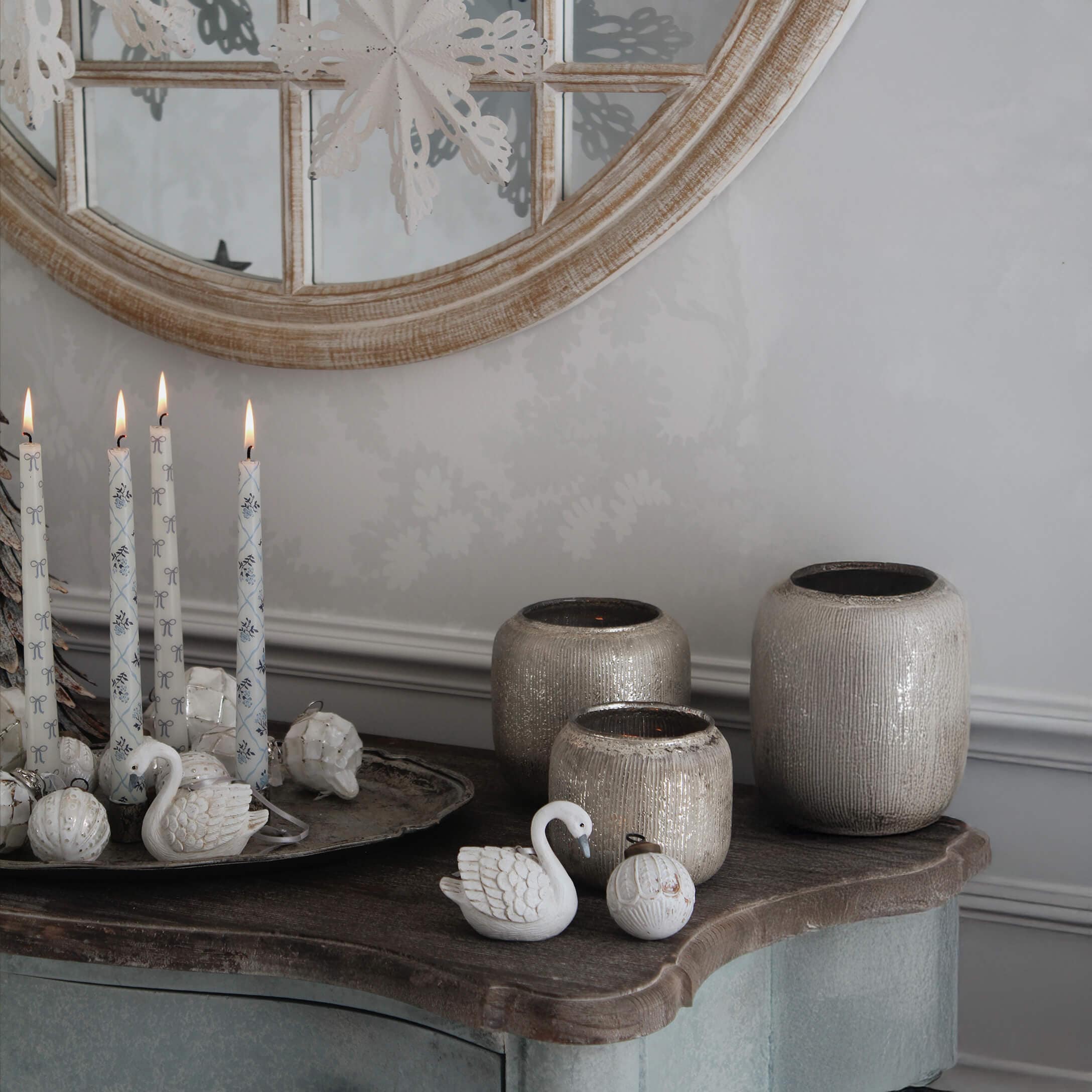 Decoratieve witte kaarsen en beige keramische vazen op houten blad met ronde spiegel op de achtergrond