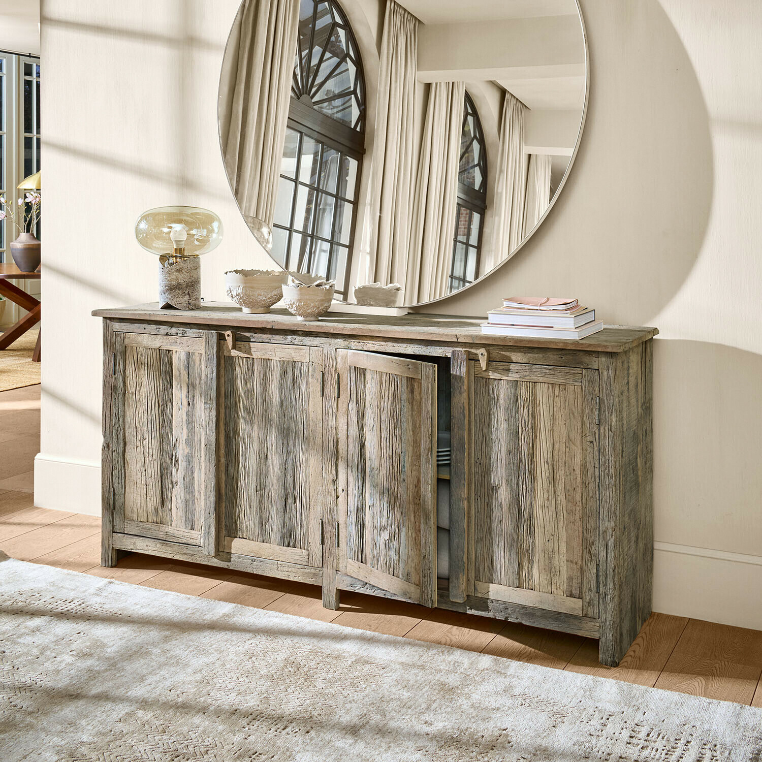 Dressoir Corvillon Rustieke grijze houten dressoir met vier deuren en grote ronde decoratieve spiegel aan de muur
