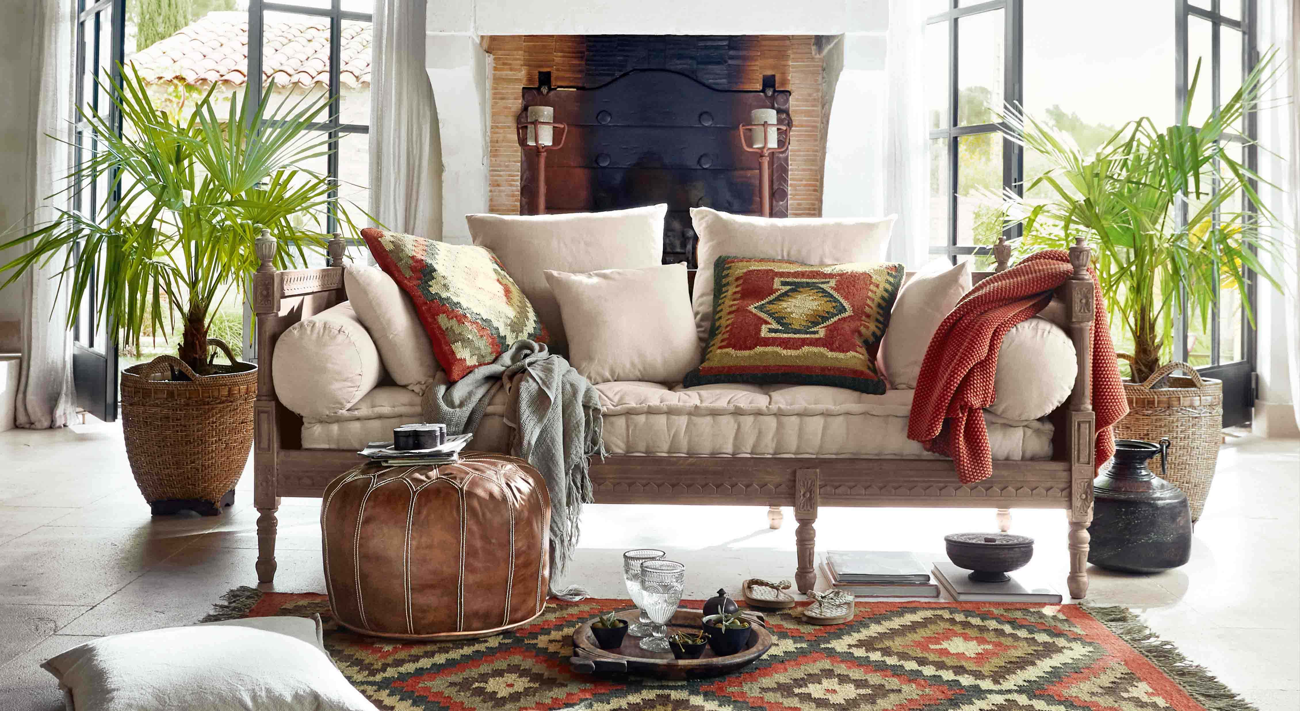 Bank met lichtbeige bekleding en houten frame, kleurrijke kussens en boho-deken in lichte woonkamer