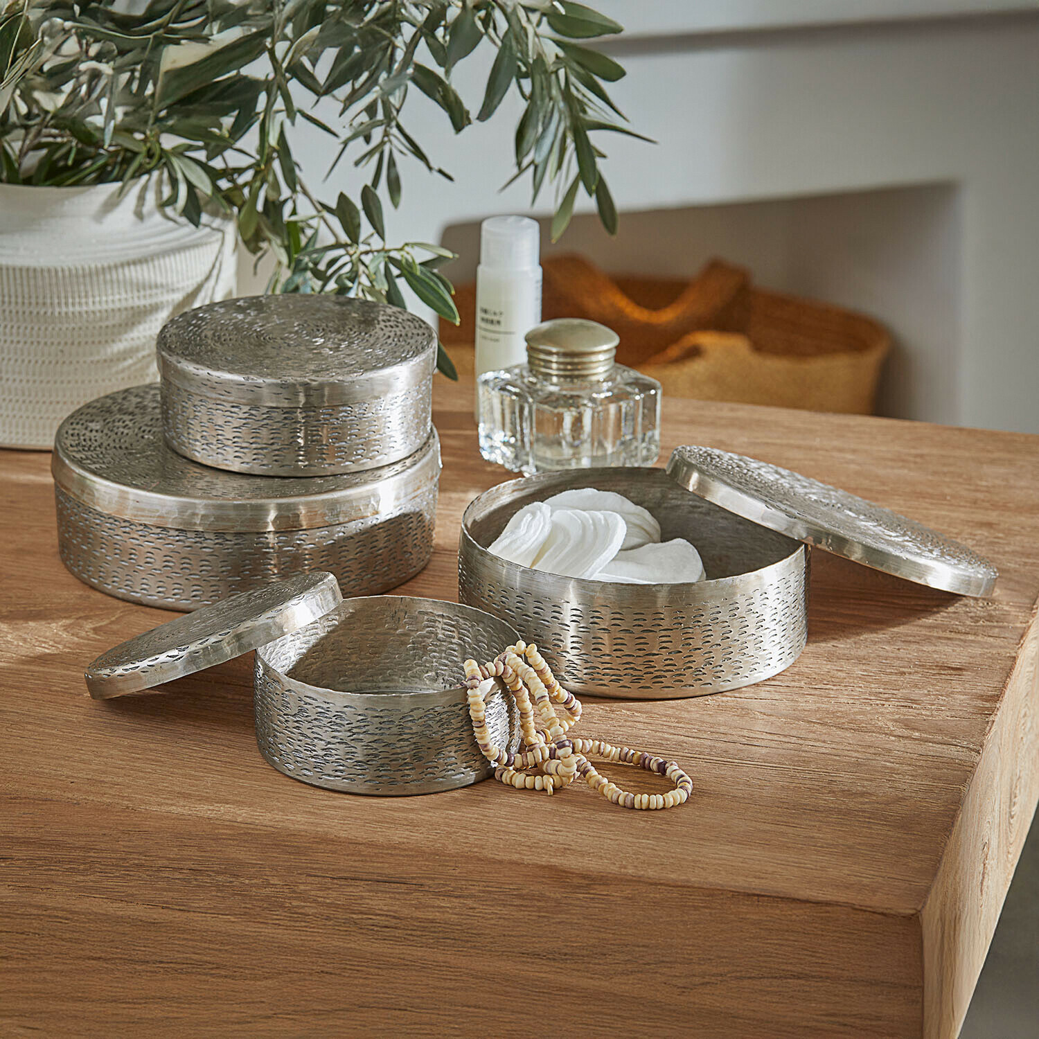 Set van drie ronde metalen zilverkleurige opbergdozen voor cosmetica en sieraden op houten tafel