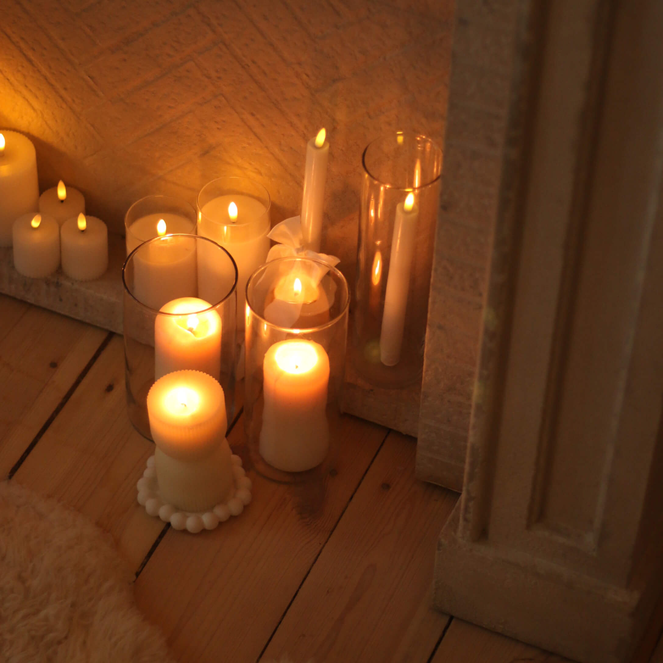 Set witte kaarsen in verschillende vormen en maten op houten vloer, interieurdecoratie