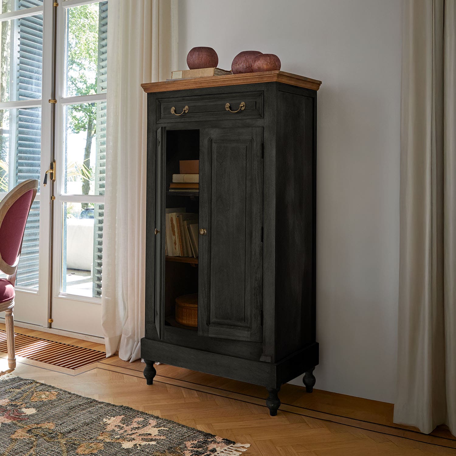 Zwarte houten kast met lichte bovenkant en messing handgrepen in klassieke woonkamer