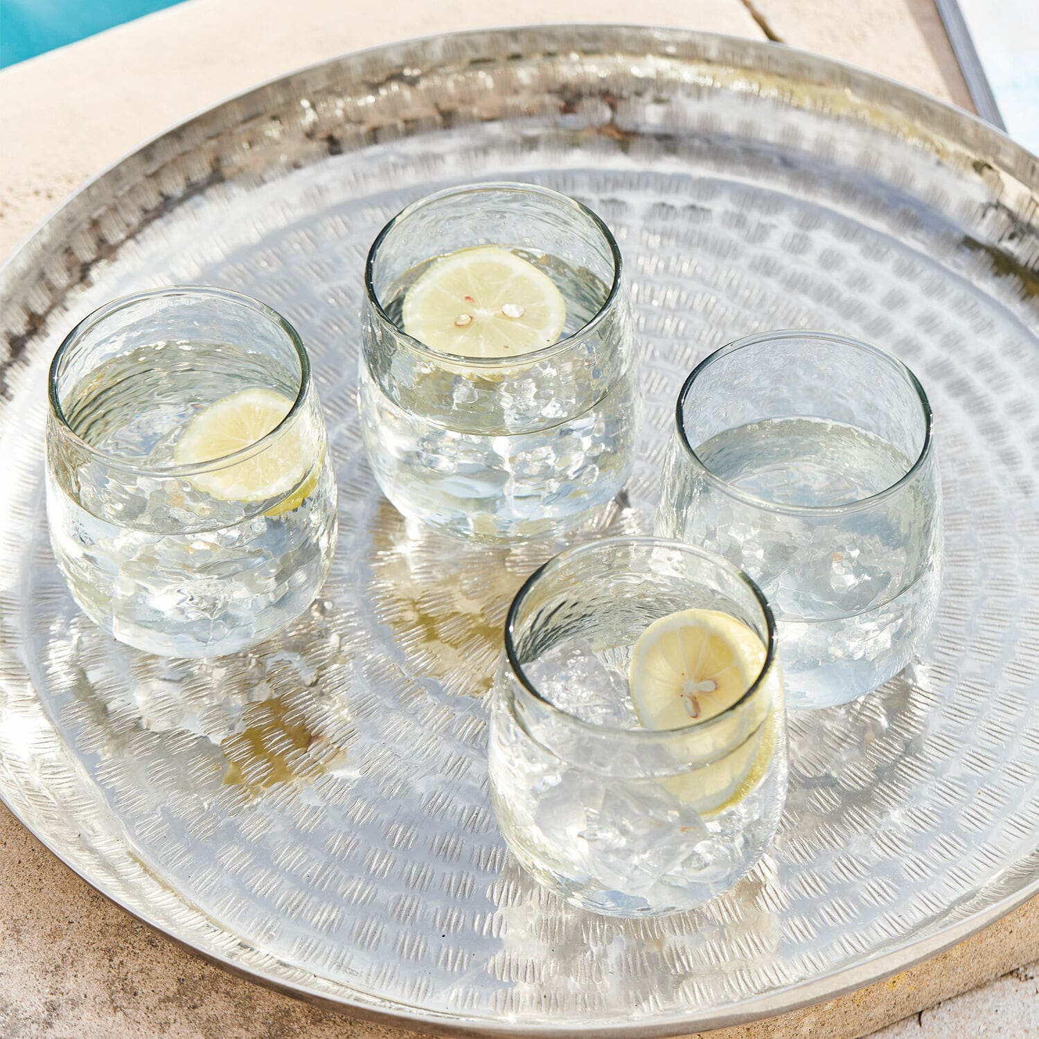 Glas set van 4 Valters Metalen dienblad met vier glazen water en schijfjes citroen bij het zwembad