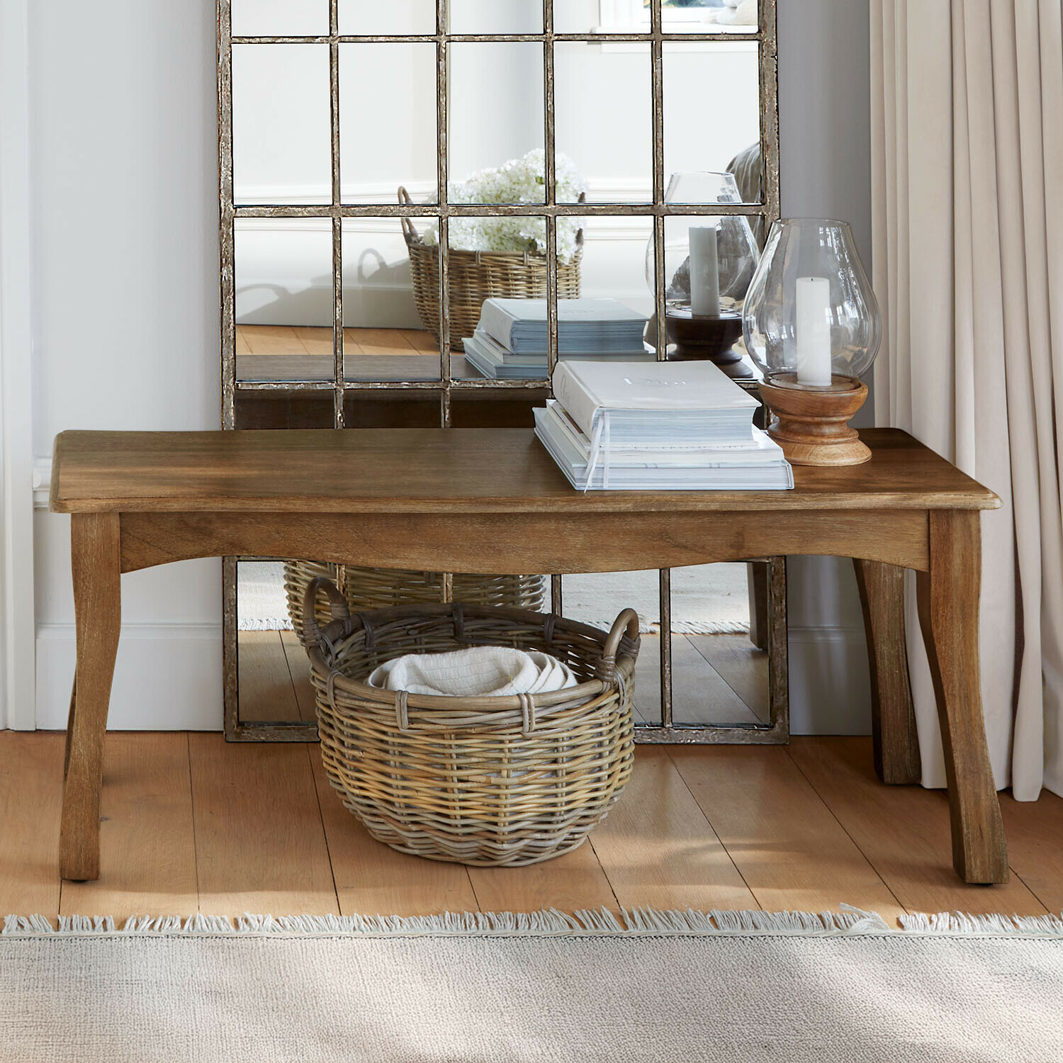 Bank van mangohout in natuurlijke kleur met rieten mand en decoratieve kandelaren